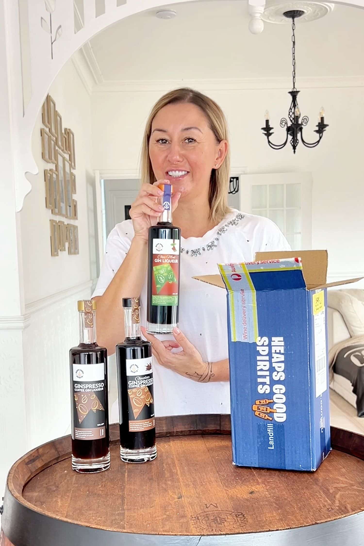 Customer holding Heaps Good Spirits gin liqueur bottles next to branded shipping box