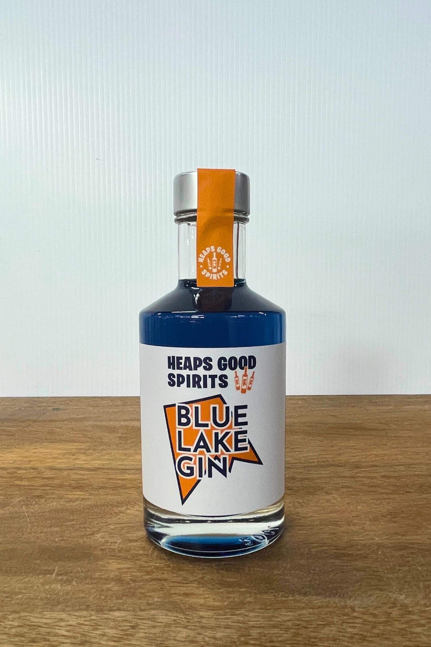 Heaps Good Spirits Blue Lake Gin bottle on wooden surface against white background