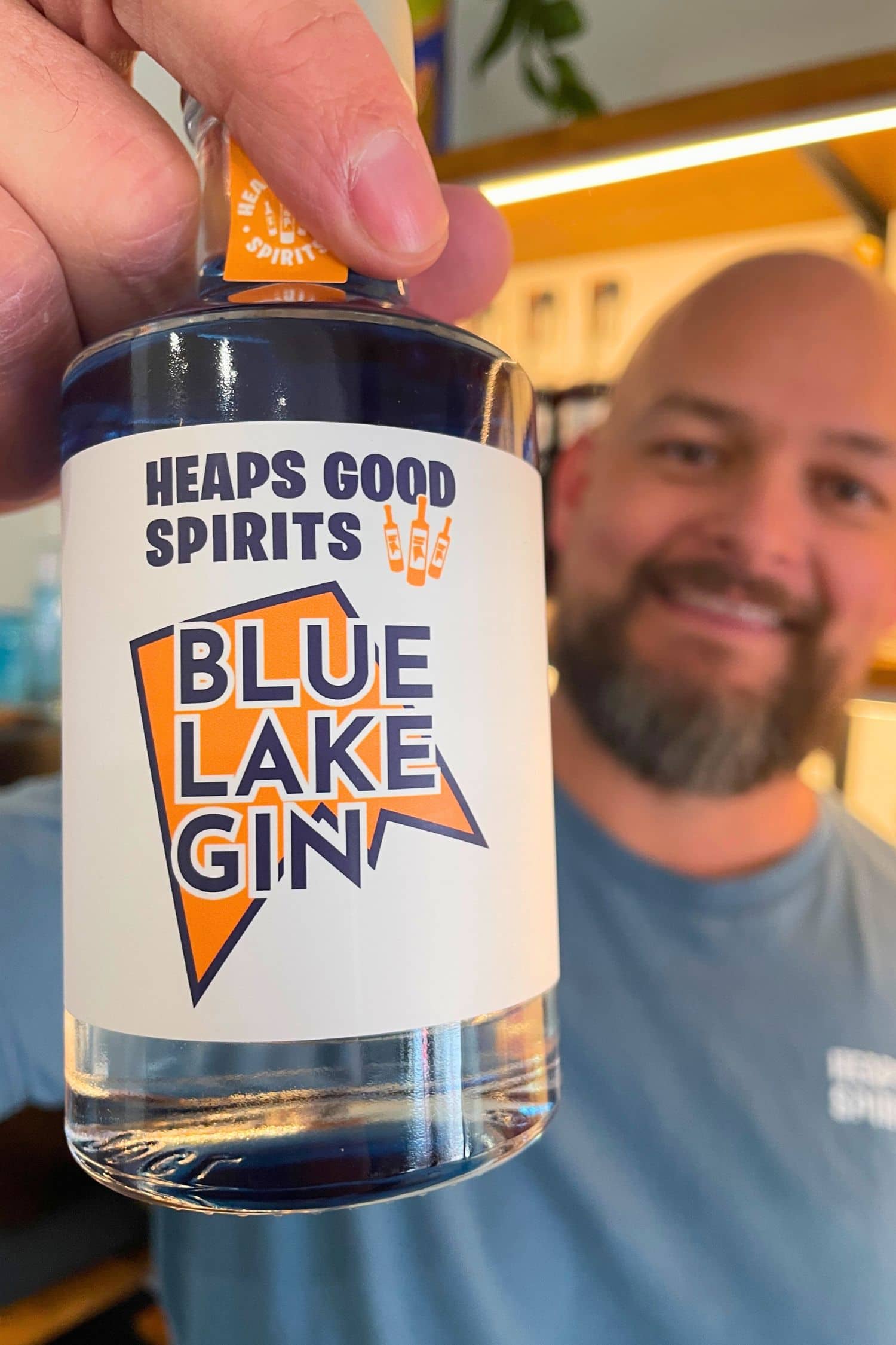 Founder holding Heaps Good Spirits Blue Lake Gin bottle inside tasting room