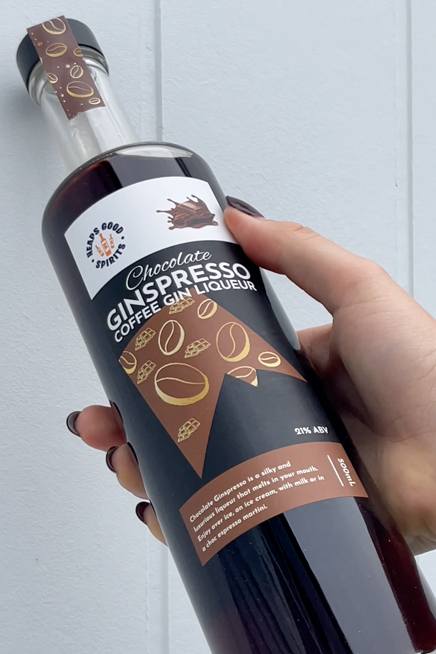 Bottle of Chocolate Ginspresso Coffee Gin Liqueur held by a hand against a light background