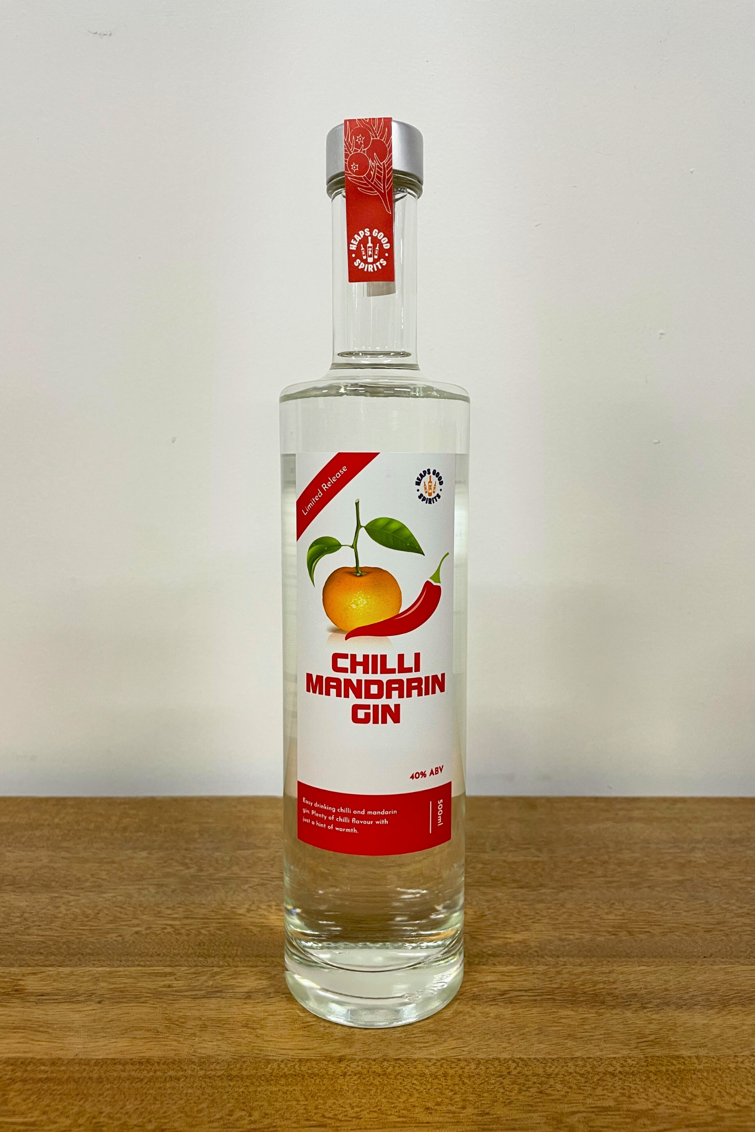 Bottle of Chilli Mandarin Gin on a wooden surface with a white background
