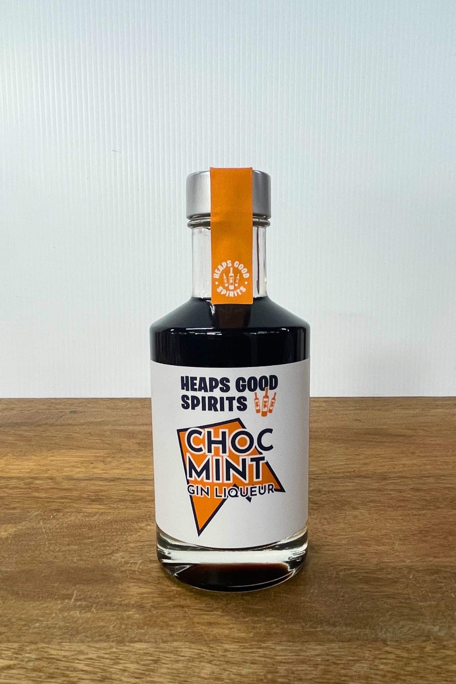 Heaps Good Spirits Choc Mint Gin Liqueur bottle on wooden surface against white background