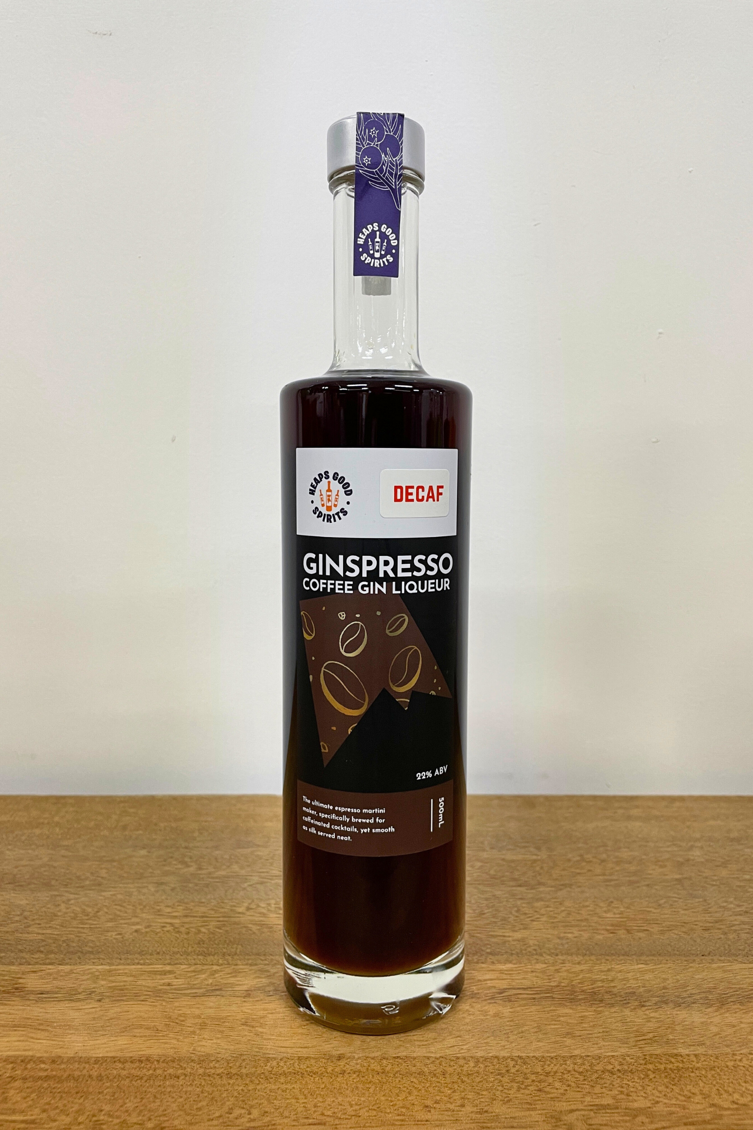 Bottle of Decaf Ginspresso Coffee Gin Liqueur on a wooden surface with a white background