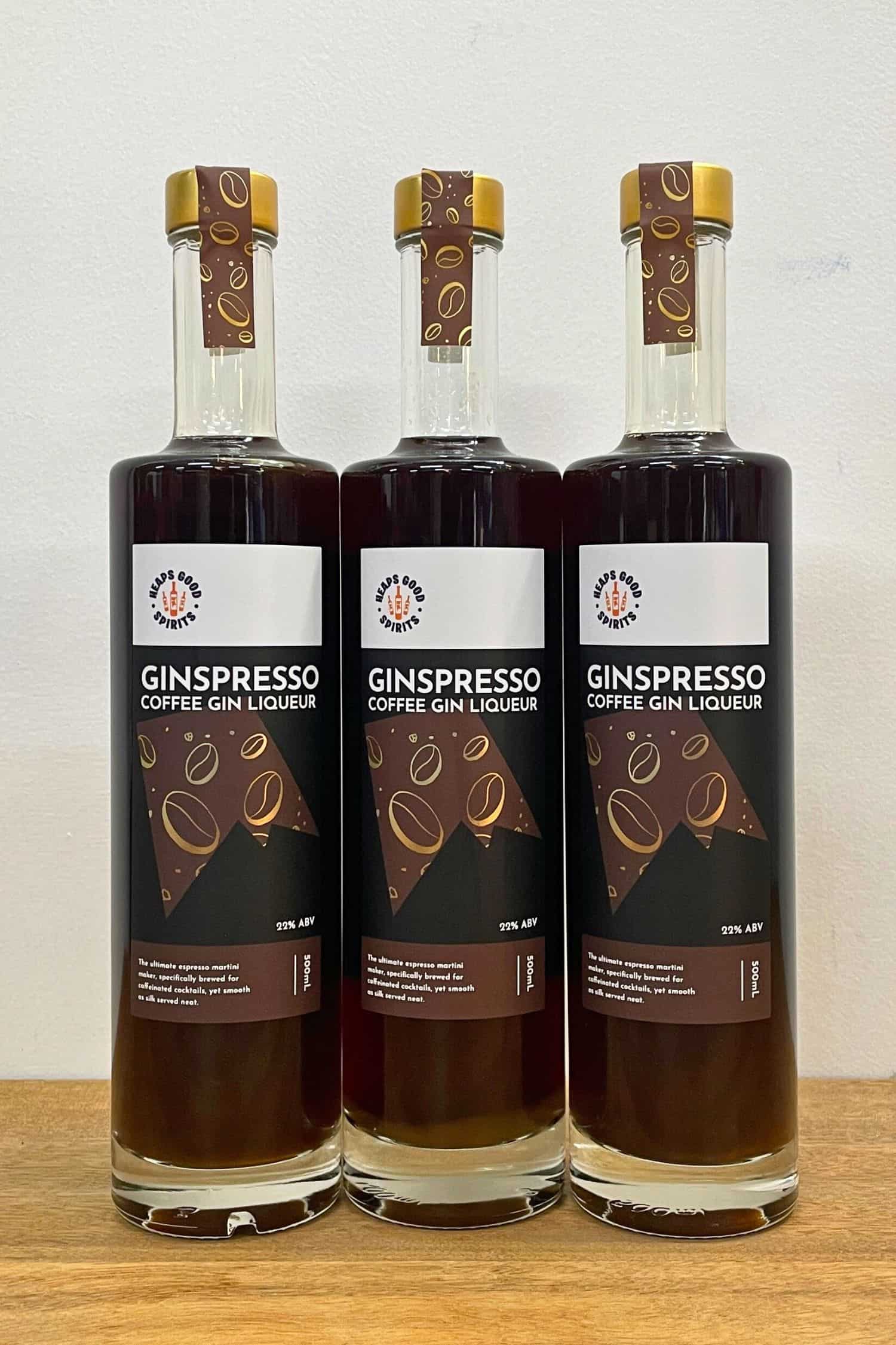 Three bottles of Ginspresso coffee gin liqueur standing side by side on wooden surface