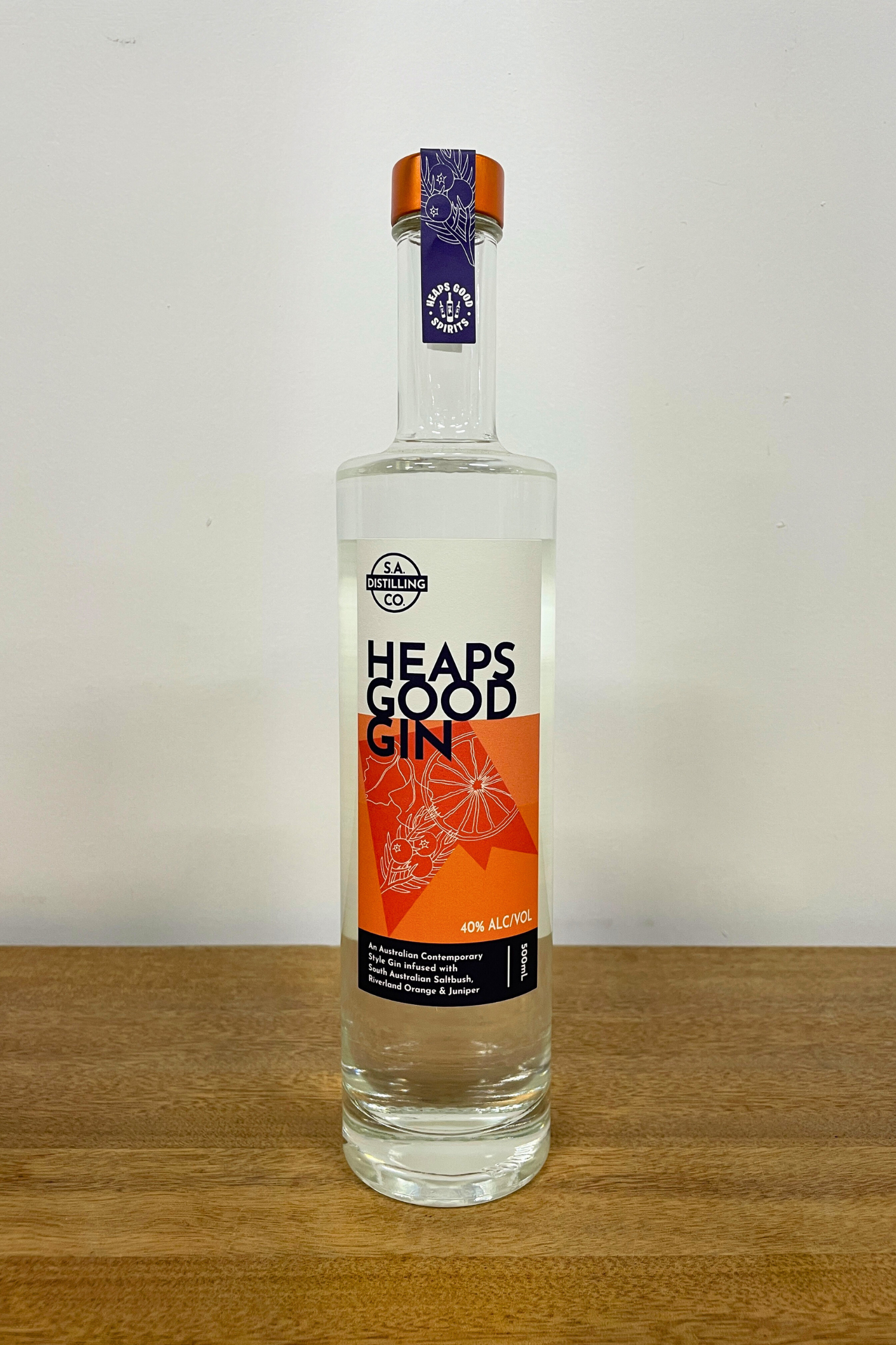 Bottle of Heaps Good Gin on a wooden surface with a white background