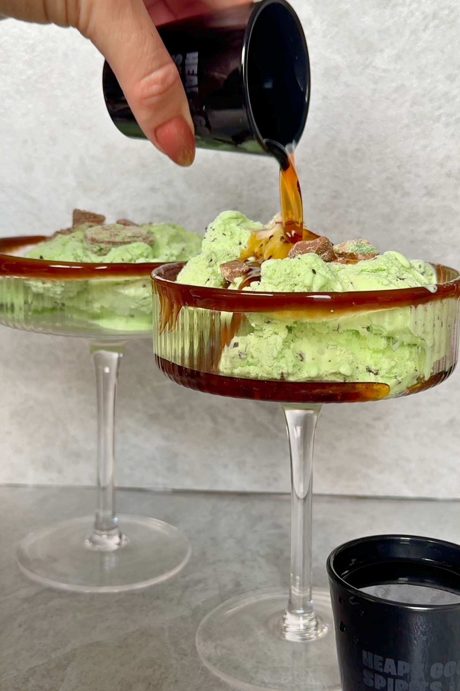 Choc Mint Gin Liqueur being poured over choc mint ice cream in a coupe cocktail glass.