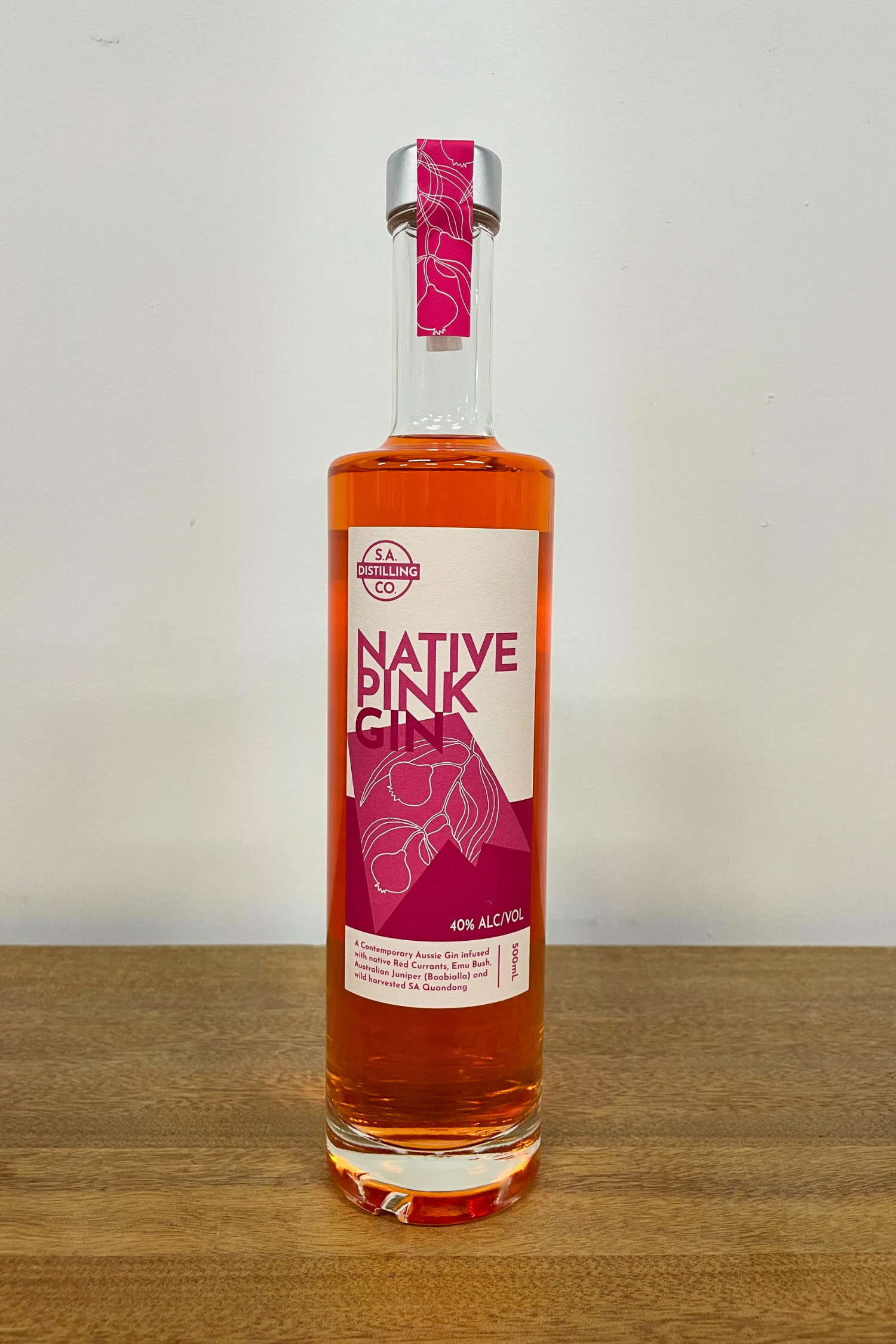 Bottle of Native Pink gin on a wooden surface with a white background
