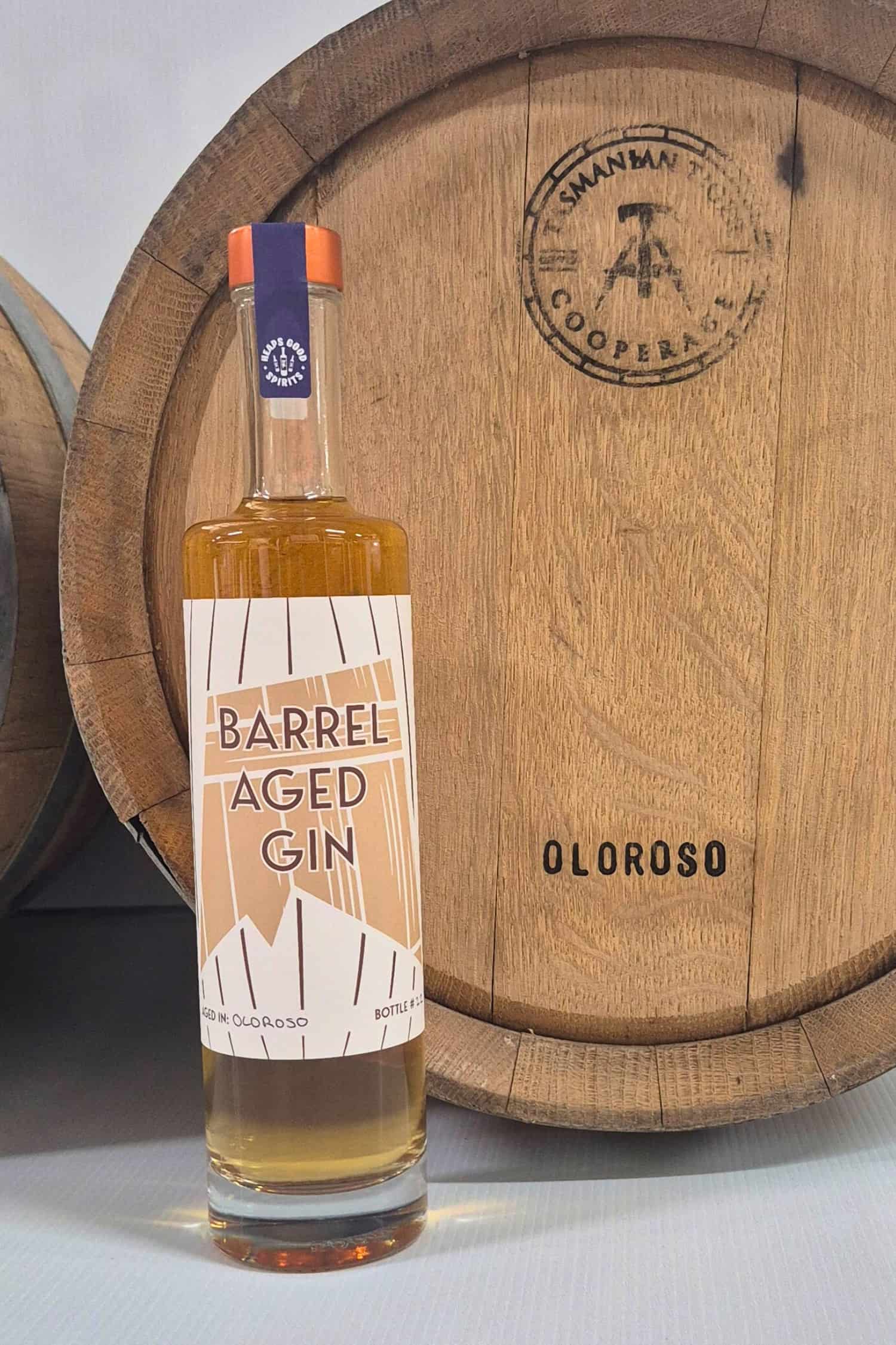 Barrel Aged Gin bottle in front of Oloroso barrel that it was aged in