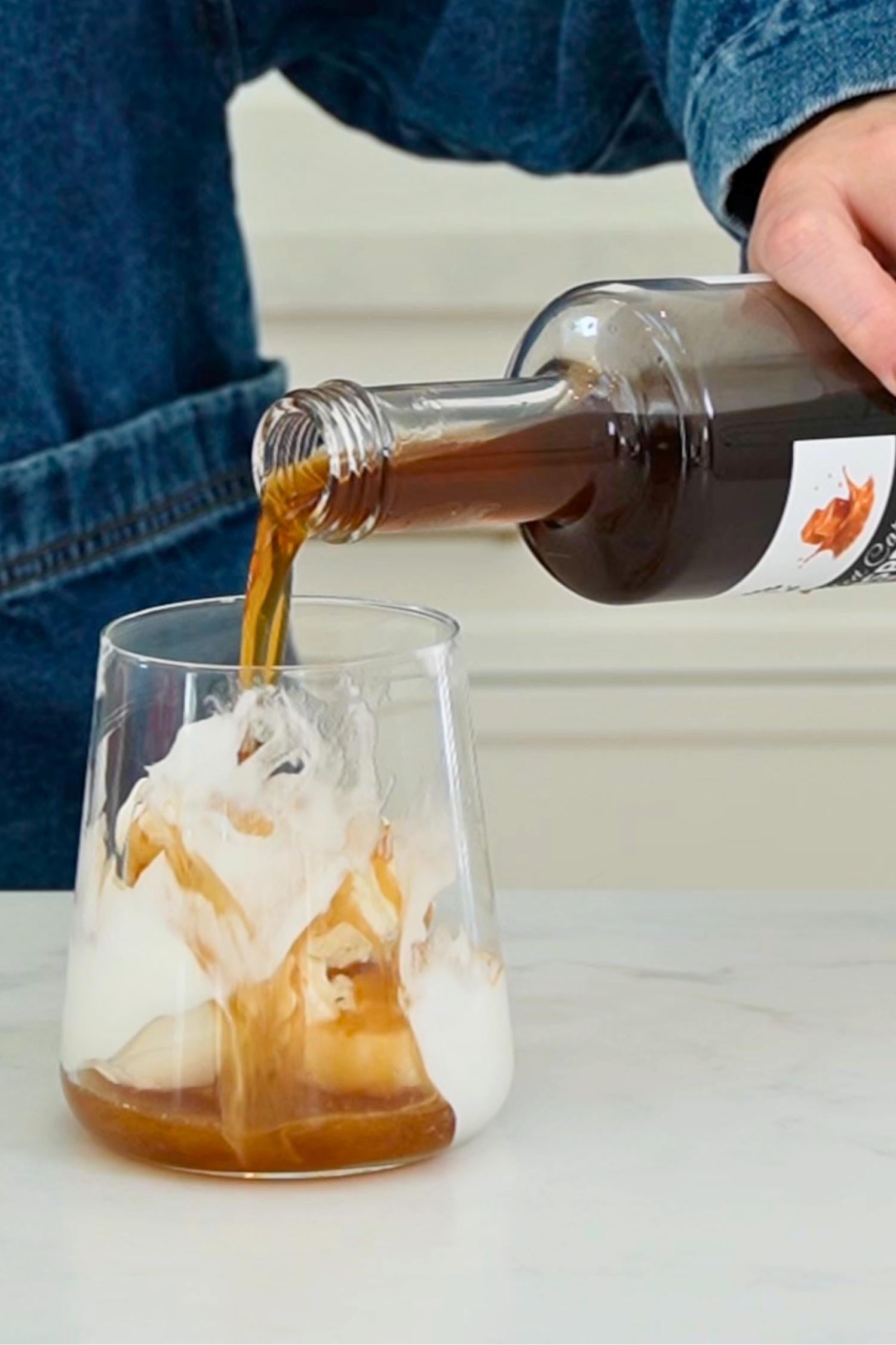 Salted Caramel Ginspresso coffee gin liqueur being poured over ice cream in a glass.