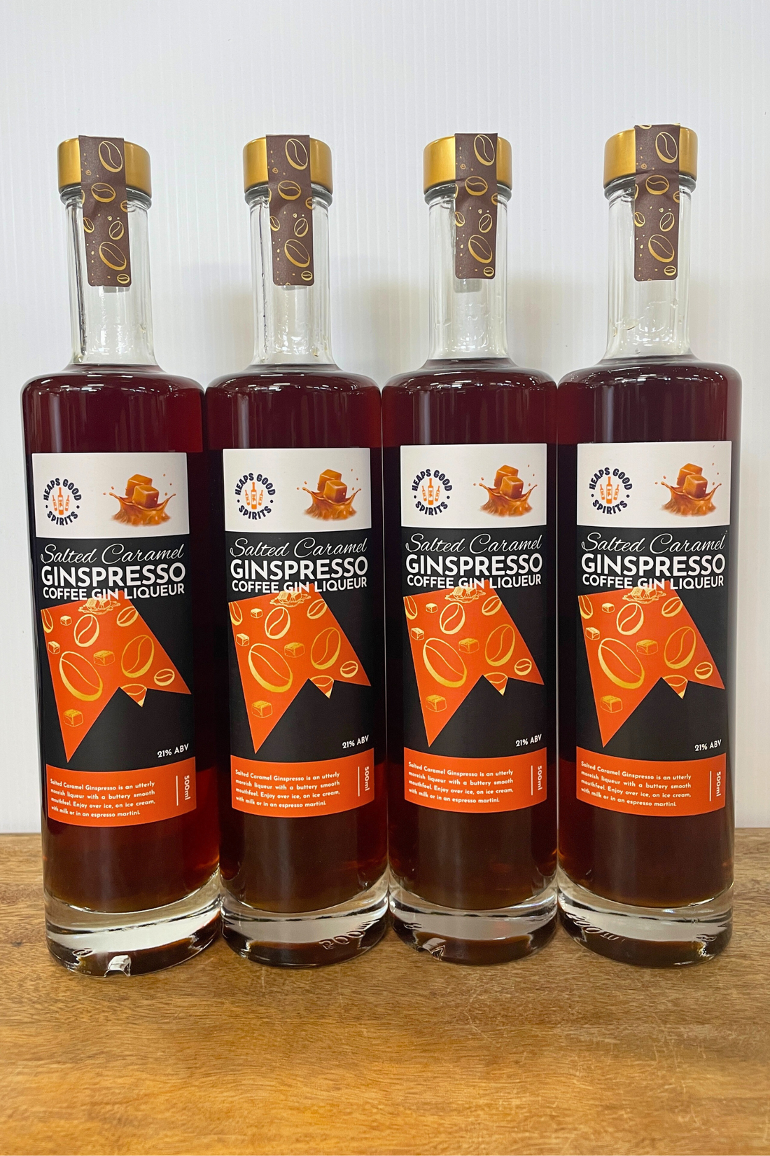 Four bottles of Salted Caramel Ginspresso on a wooden surface with a white background.
