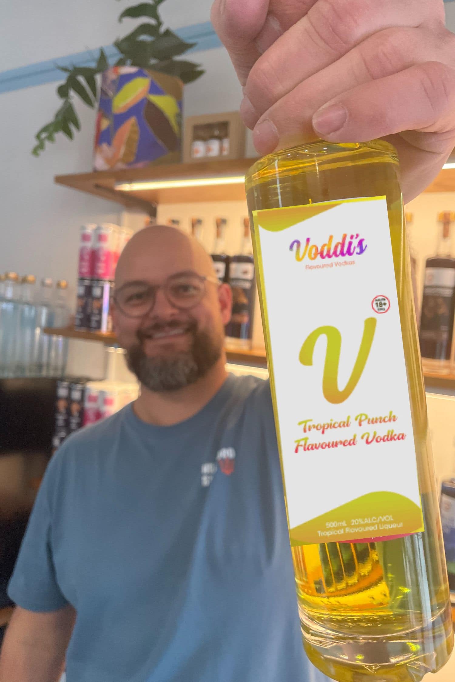 Founder holding Voddi’s Tropical Punch Flavoured Vodka bottle inside Heaps Good Spirits tasting room