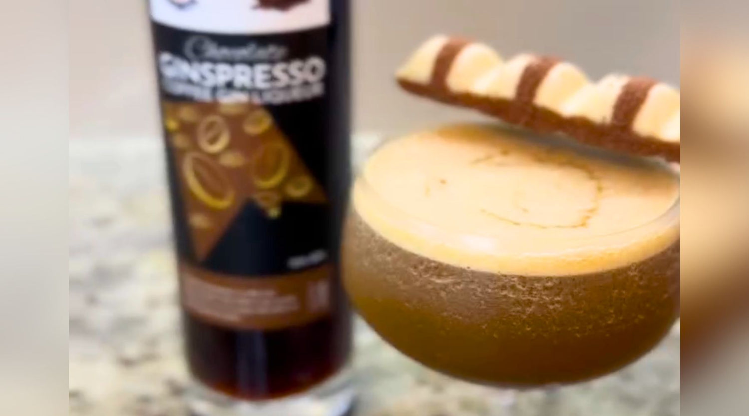 Kinder Bueno Espresso Martini, garnished with Kinder Bueno chocolate bar and with bottle of Chocolate Ginspresso beside it.