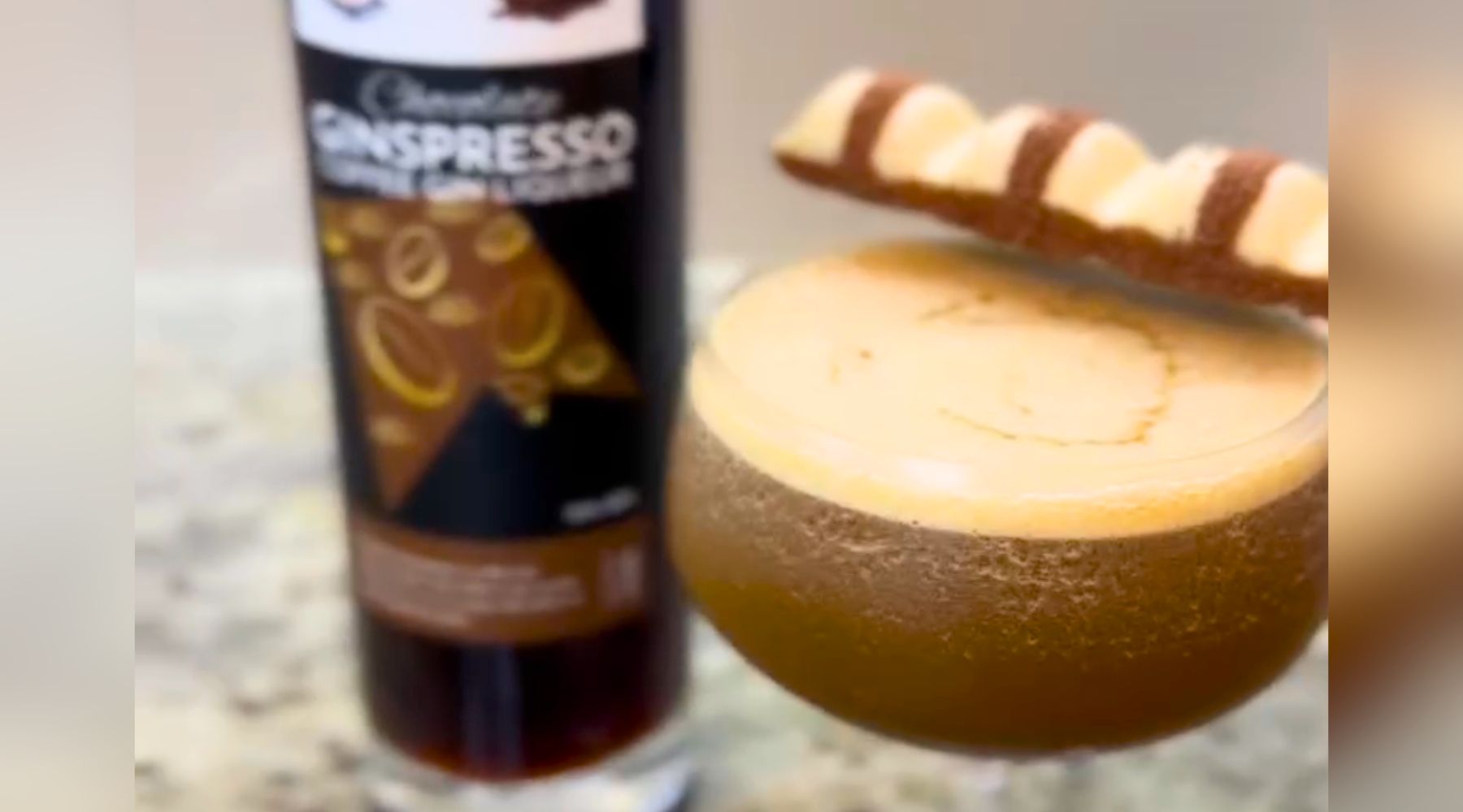 Kinder Bueno Espresso Martini, garnished with Kinder Bueno chocolate bar and with bottle of Chocolate Ginspresso beside it.