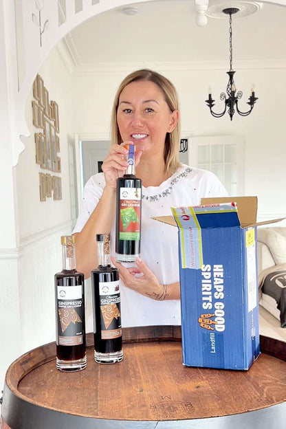 Customer holding Heaps Good Spirits gin liqueur bottles next to branded shipping box