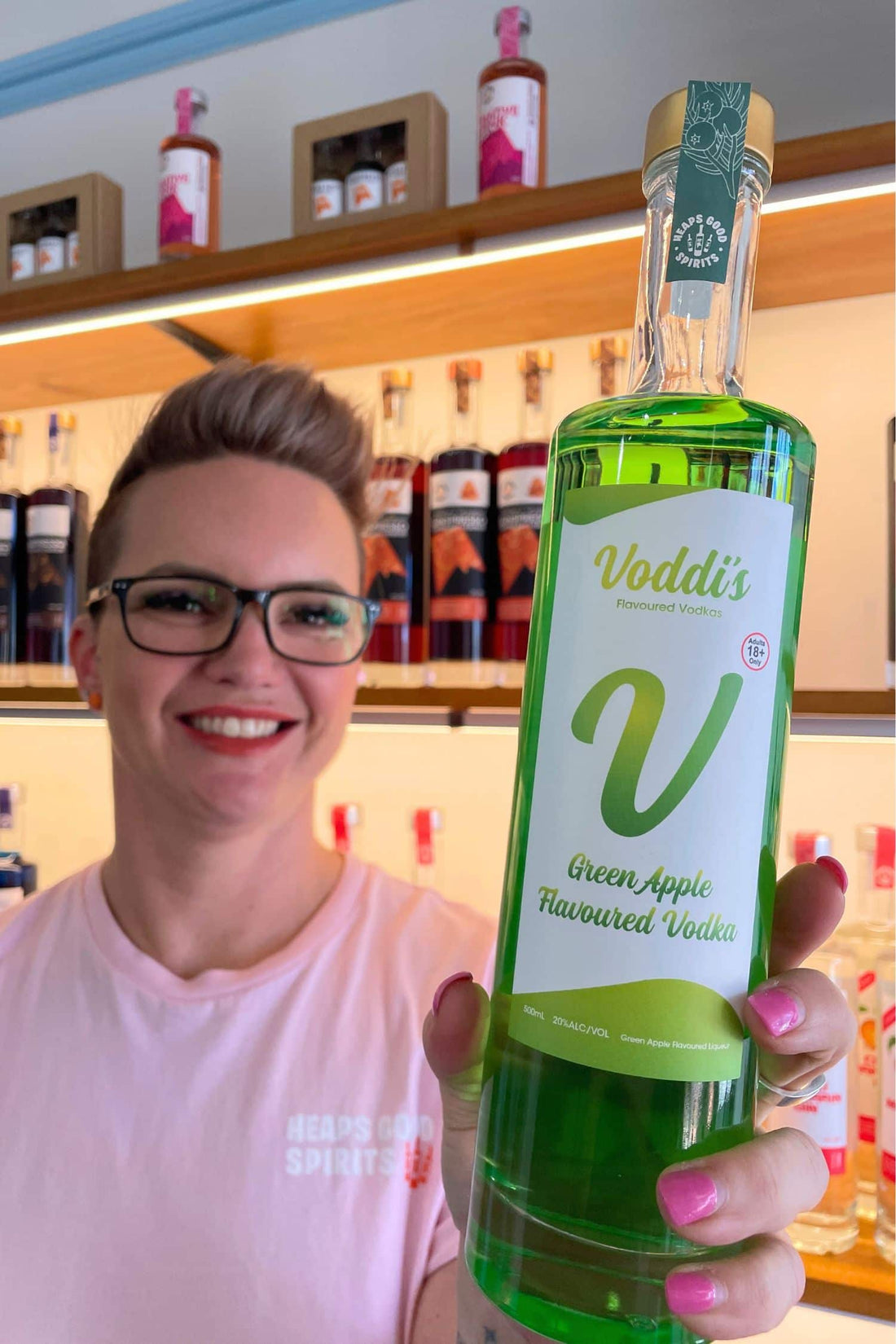 Founder holding Voddi’s Green Apple Flavoured Vodka bottle inside Heaps Good Spirits tasting room