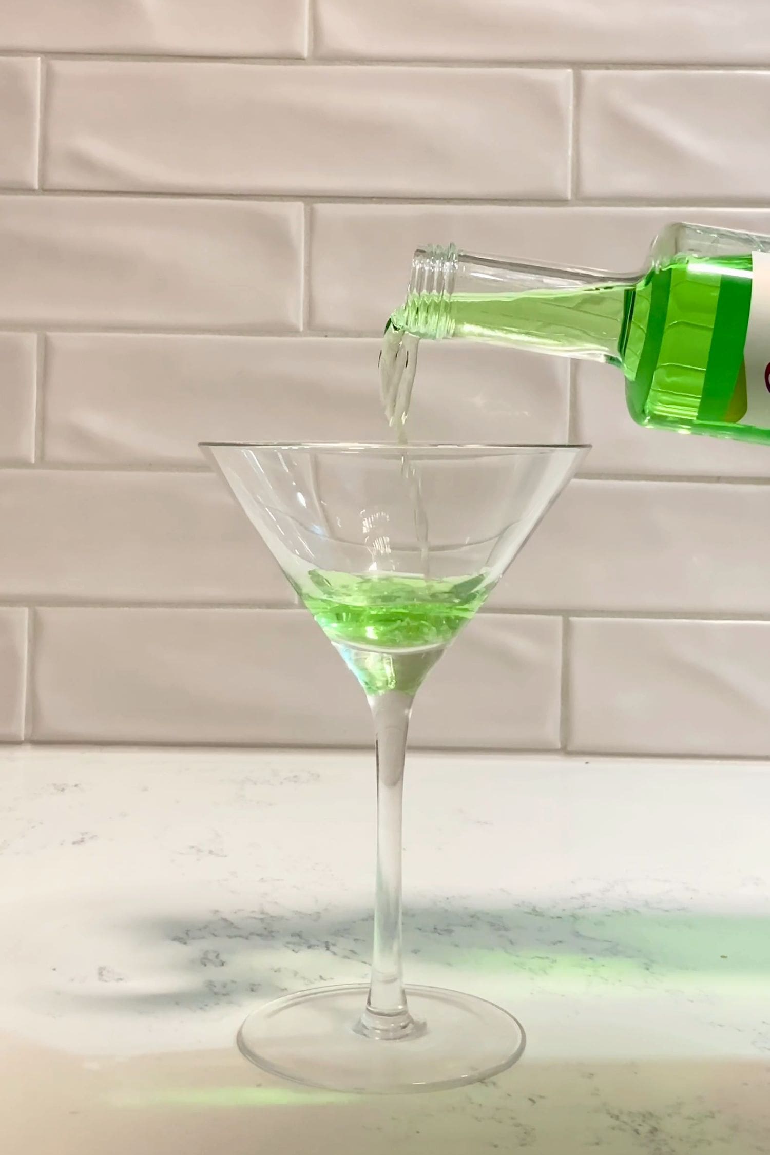 Voddi’s Green Apple Flavoured Vodka being poured into a martini glass on kitchen bench