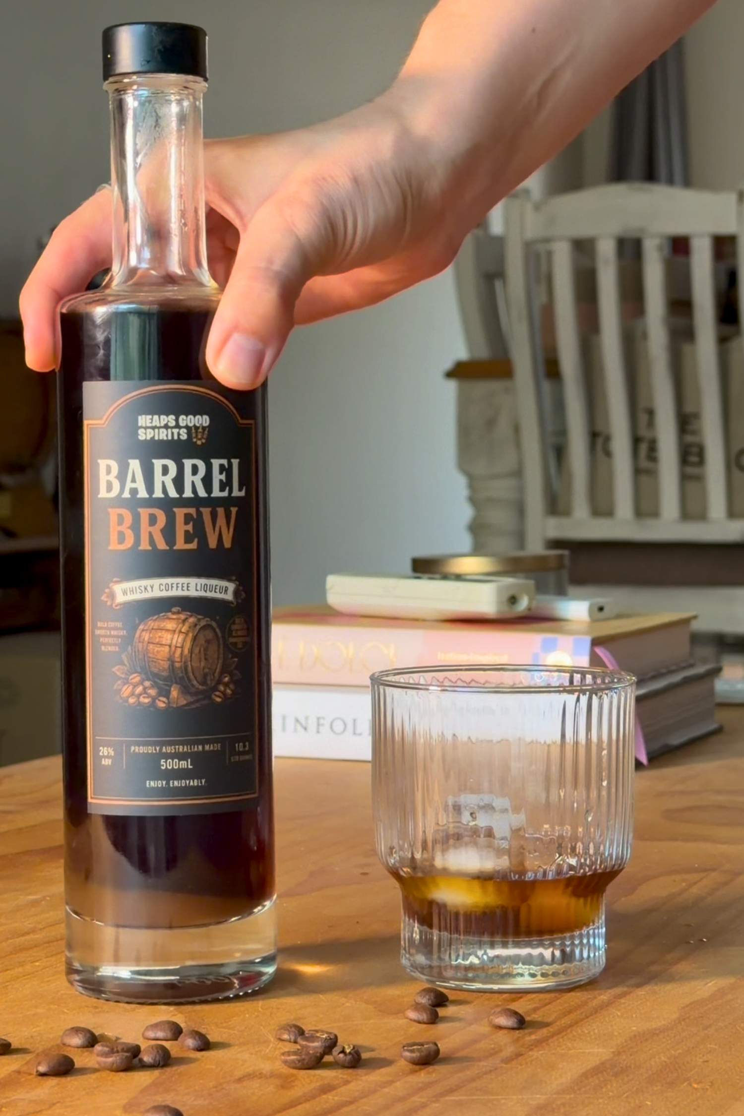 Bottle of Barrel Brew whisky coffee liqueur on a coffee table next to a whisky glass over ice, highlighting the premium Australian-made coffee liqueur.