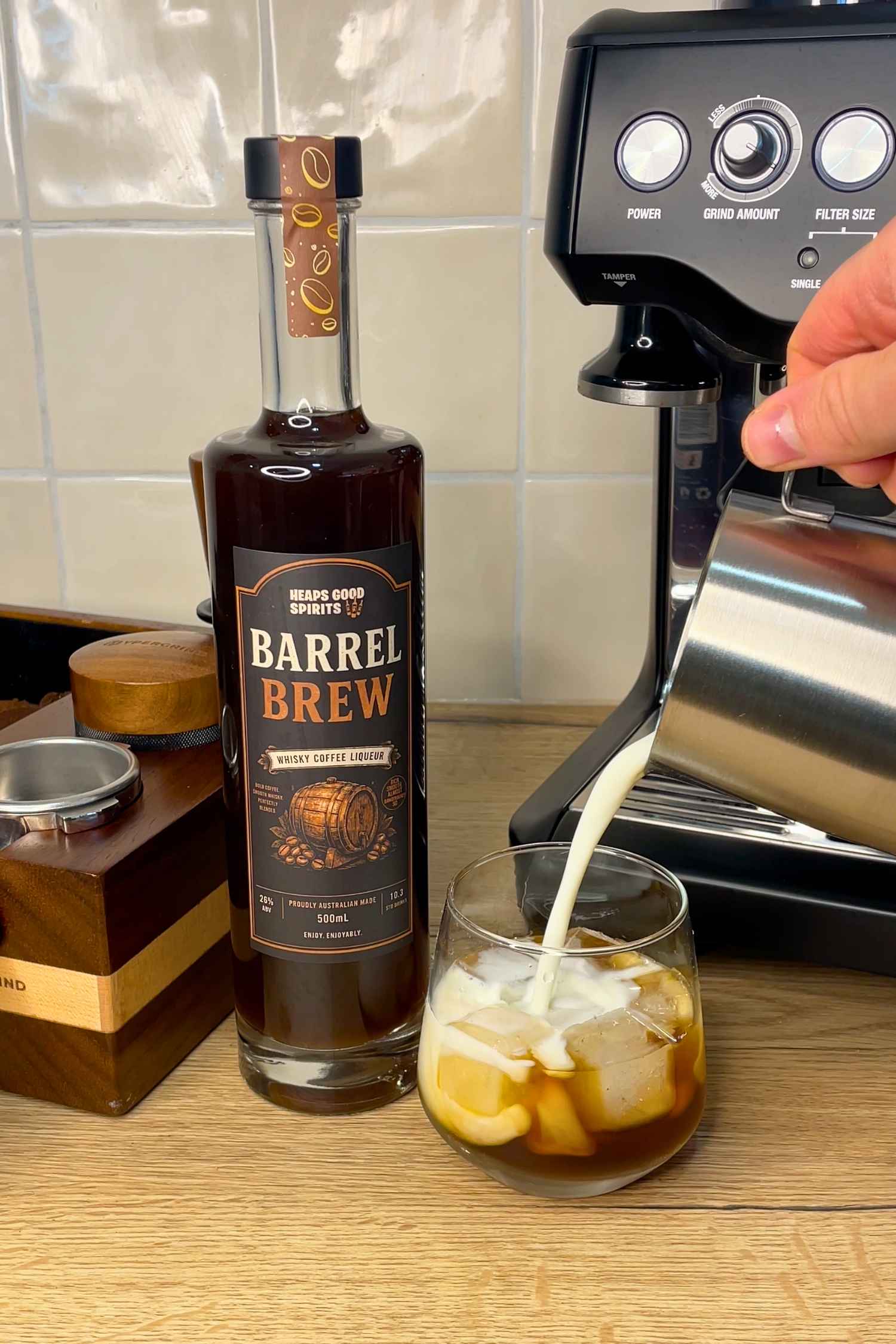 Barrel Brew whisky coffee liqueur being poured over ice and topped with milk beside an espresso machine for a smooth coffee-inspired serve.