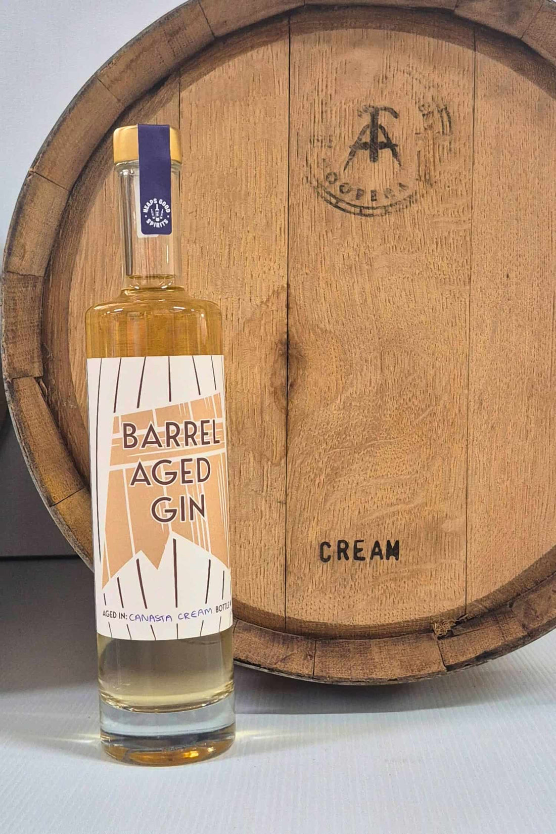 Barrel Aged Gin bottle in front of Canasta Cream barrel that it was aged in