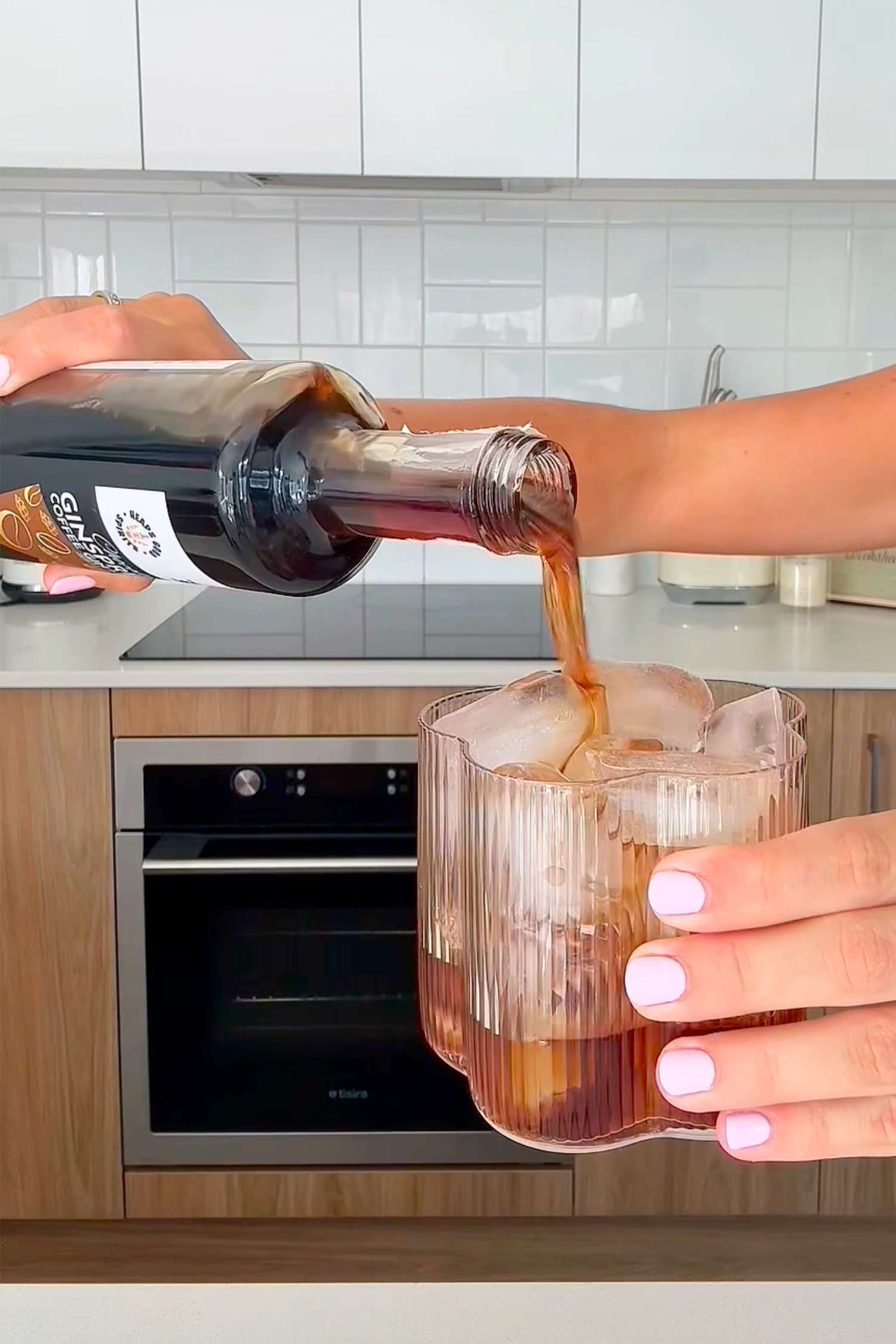 Person pouring Chocolate Ginspresso coffee gin liqueur straight over ice in a glass.