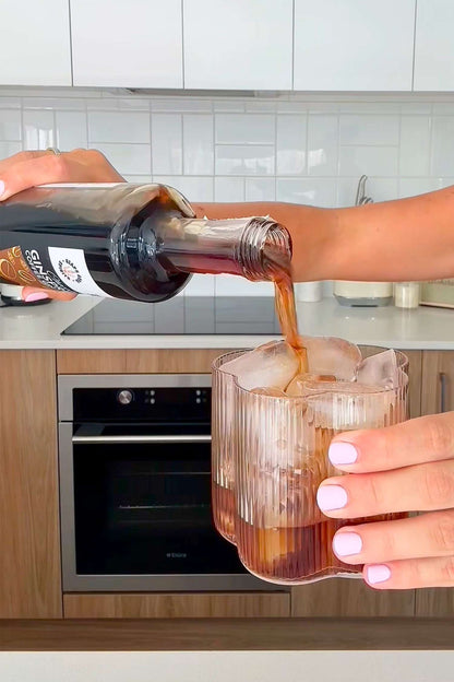 Person pouring Chocolate Ginspresso coffee gin liqueur straight over ice in a glass.