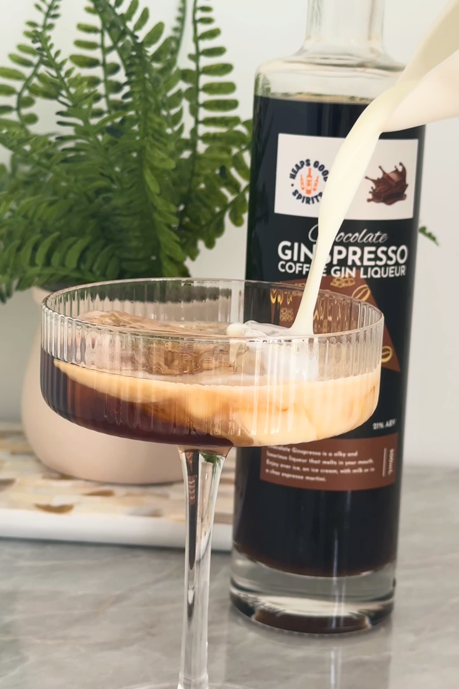 Milk being poured into Chocolate Ginspresso coffee cocktail in coupe glass