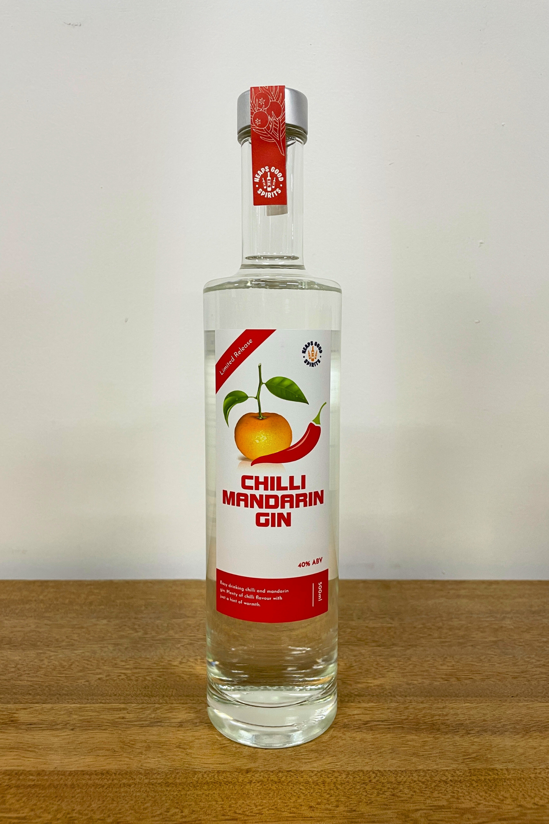 Bottle of Chilli Mandarin Gin on a wooden surface with a white background