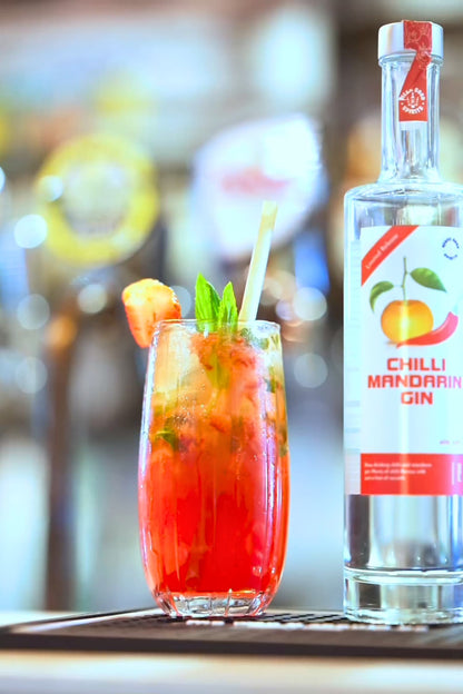 Chilli Mandarin Gin bottle beside red mandarin cocktail with mint garnish