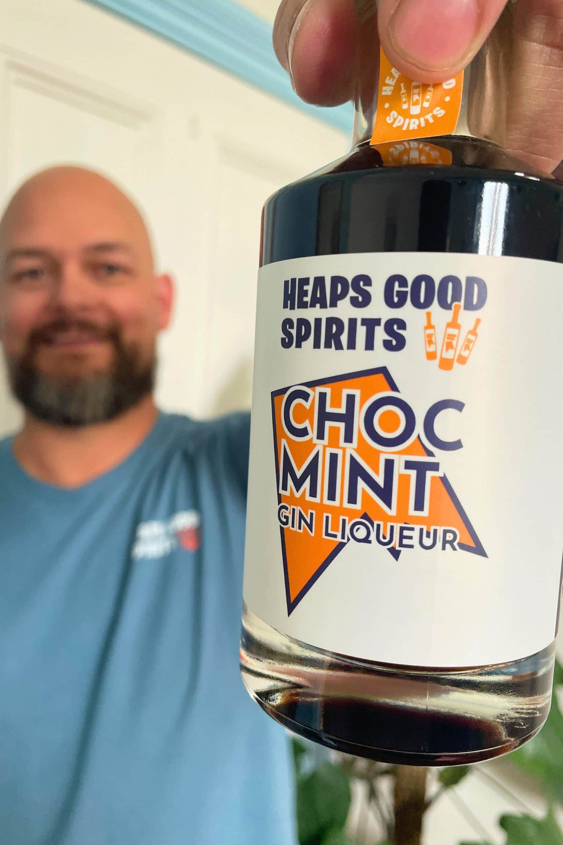 Founder holding Heaps Good Spirits Choc Mint Gin Liqueur bottle indoors