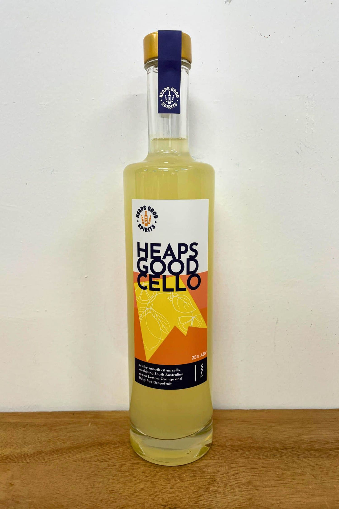 Heaps Good Cello citrus liqueur bottle on wooden surface against white background