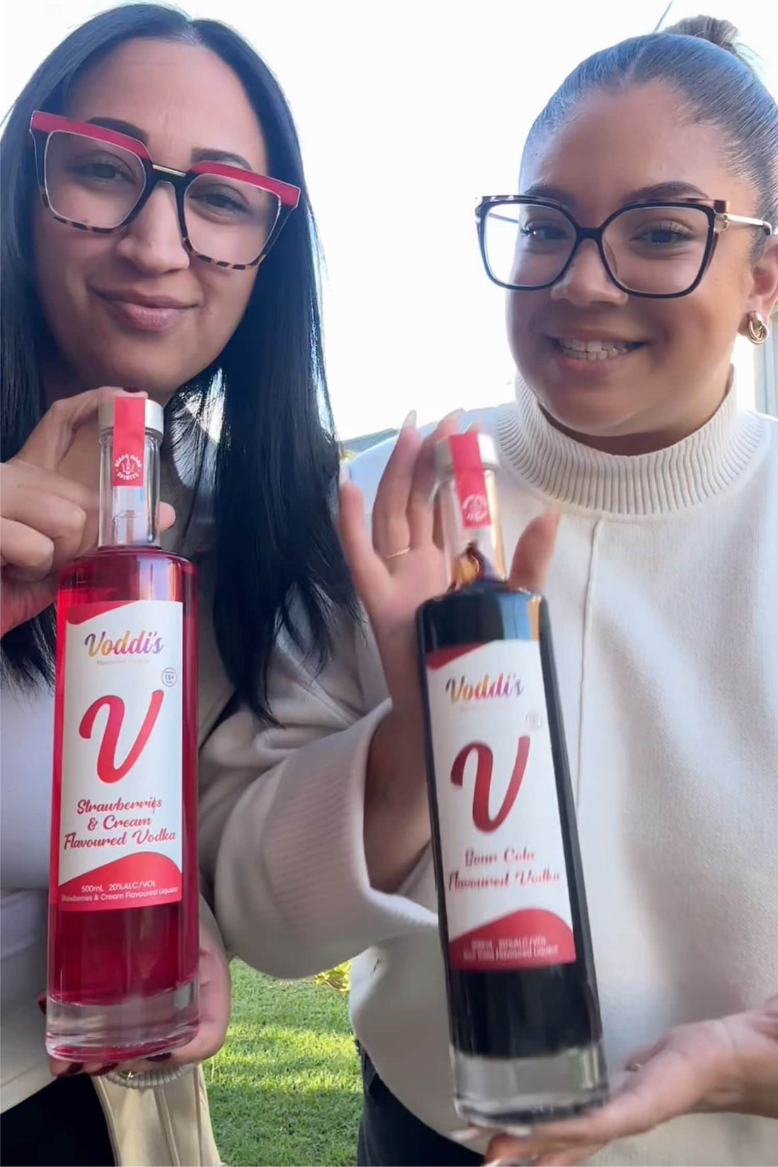 Two customers holding Voddi’s Sour Cola Flavoured Vodka and Strawberries &amp; Cream Vodka bottles outdoors