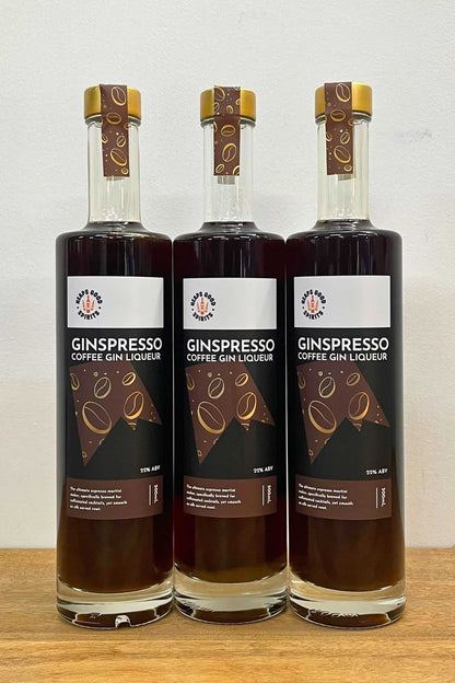 Three bottles of Ginspresso coffee gin liqueur standing side by side on wooden surface