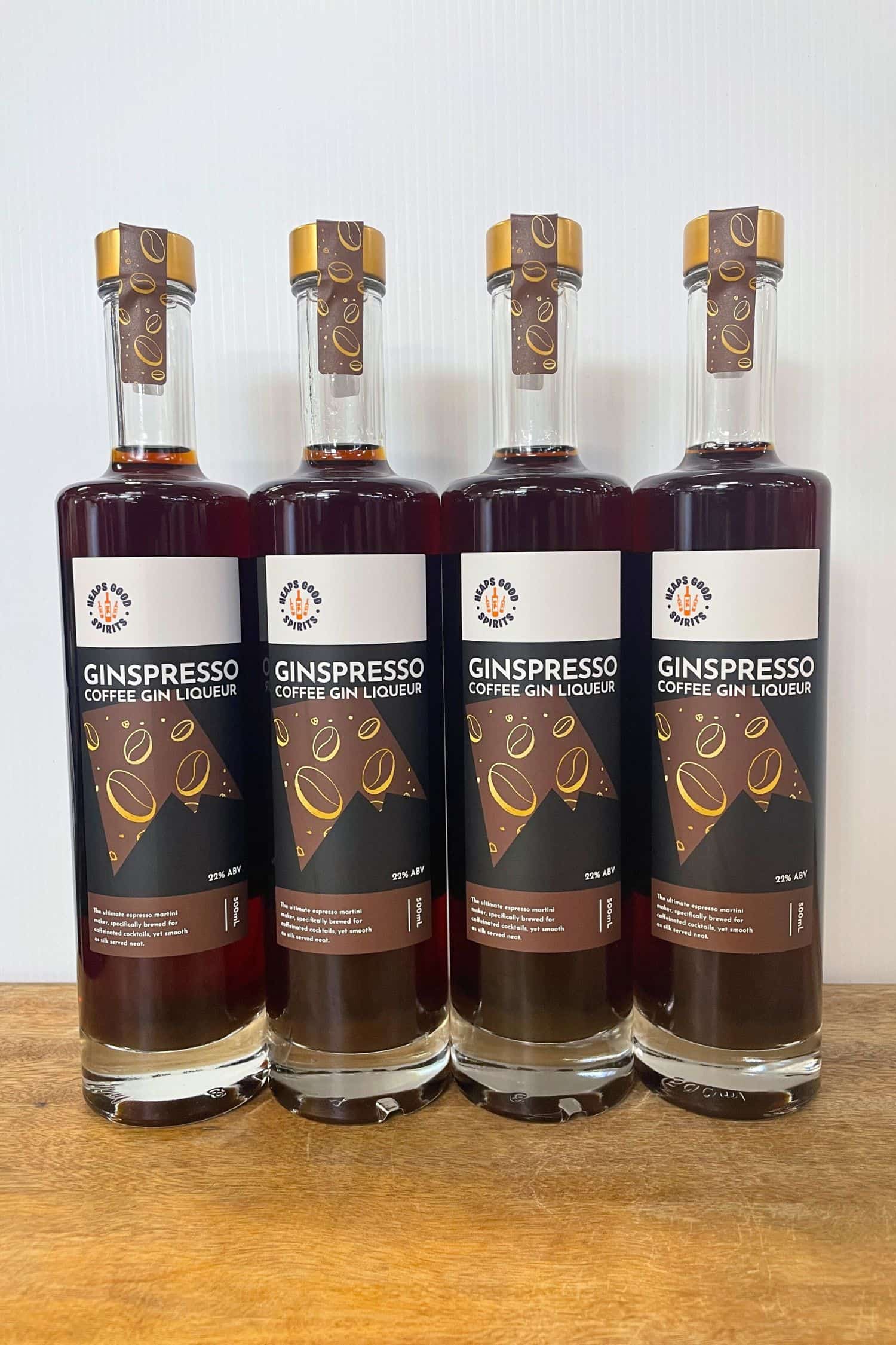Four bottles of Ginspresso coffee gin liqueur lined up on wooden surface