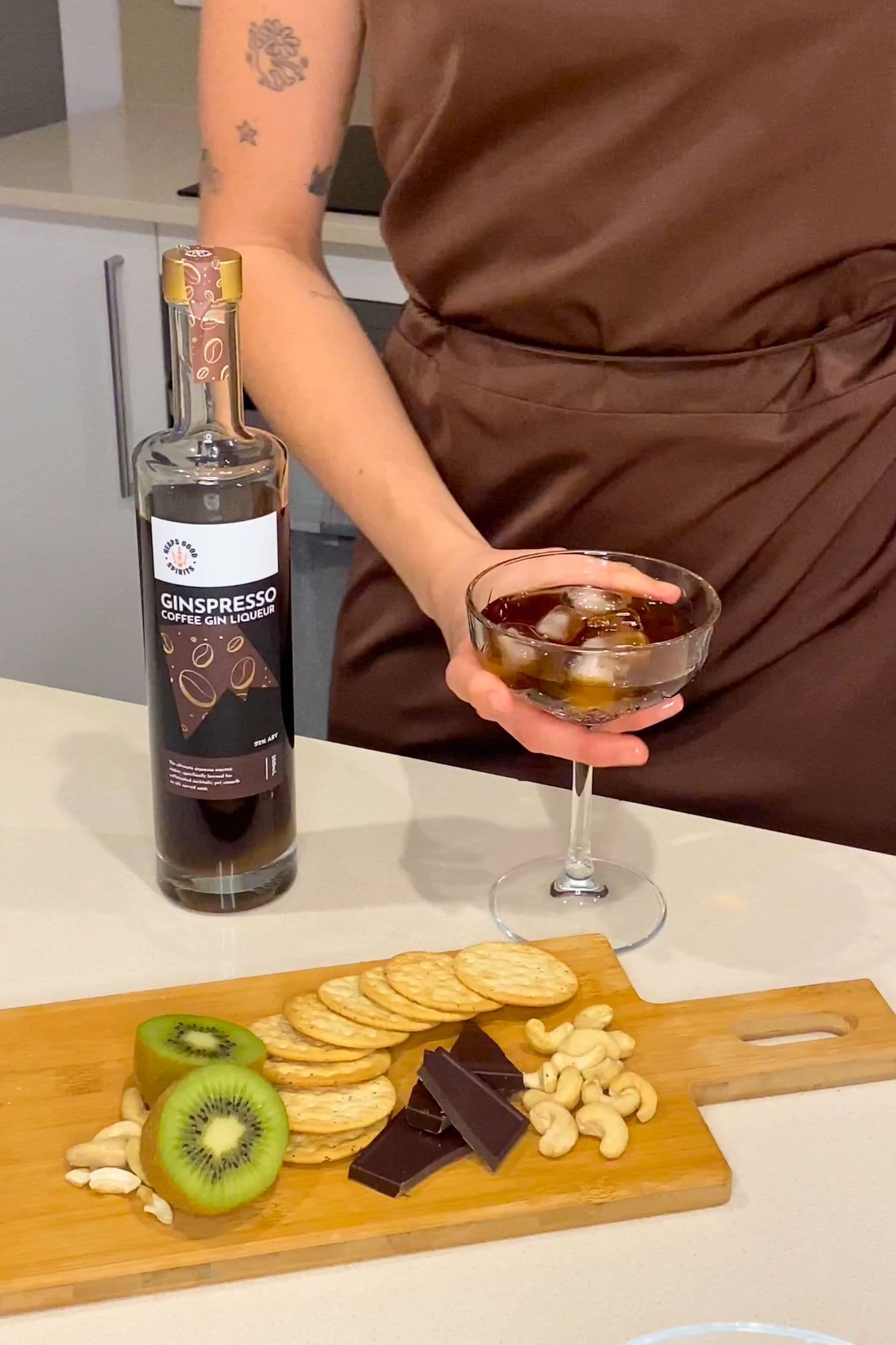 Ginspresso coffee gin liqueur served over ice with chocolate, cashews and fruit on a grazing board.