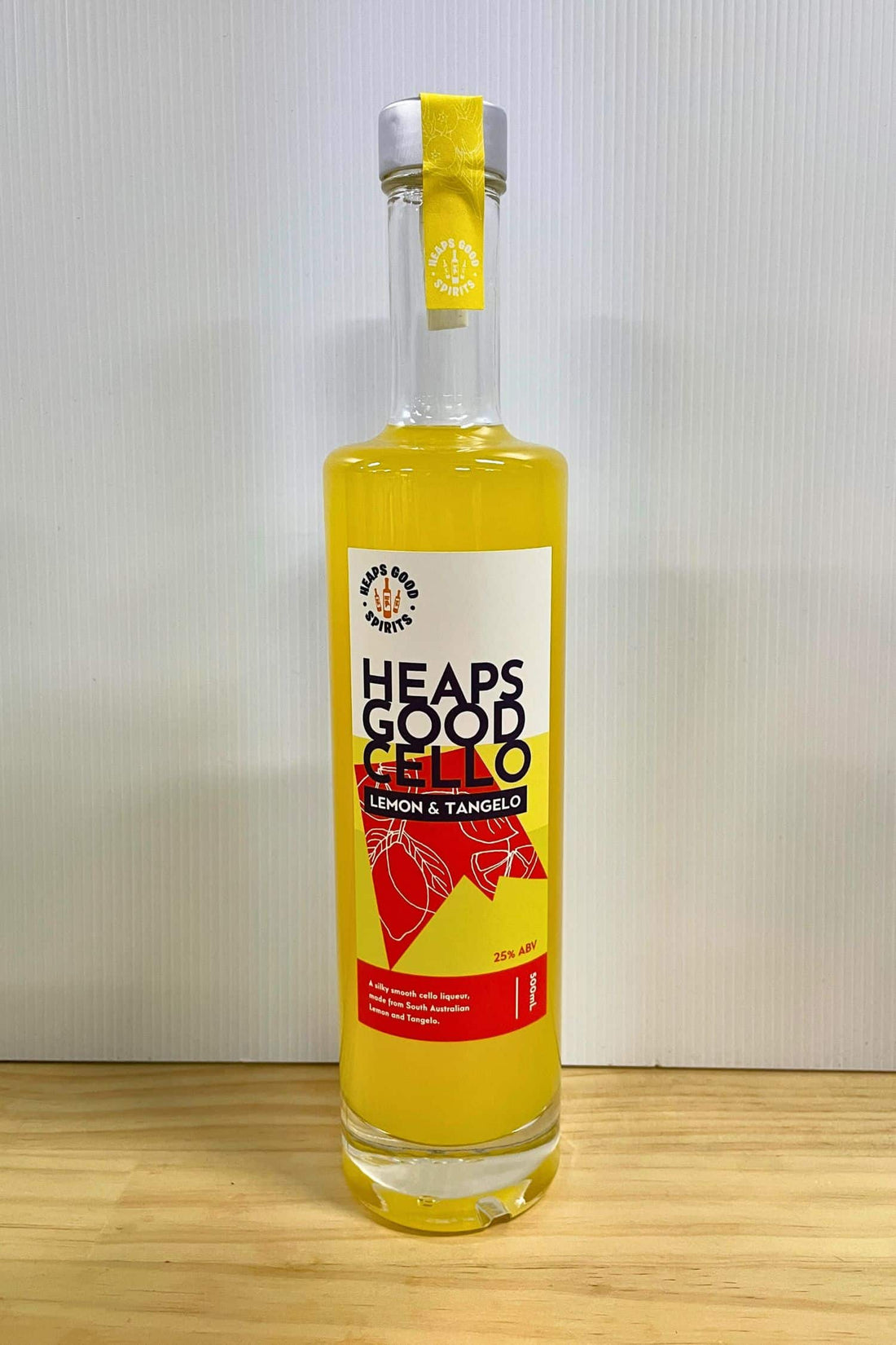 Heaps Good Cello Lemon &amp; Tangelo liqueur 500ml bottle on wooden surface against white background