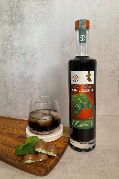 Bottle of Gin Liqueur with a glass of the drink on a wooden board.