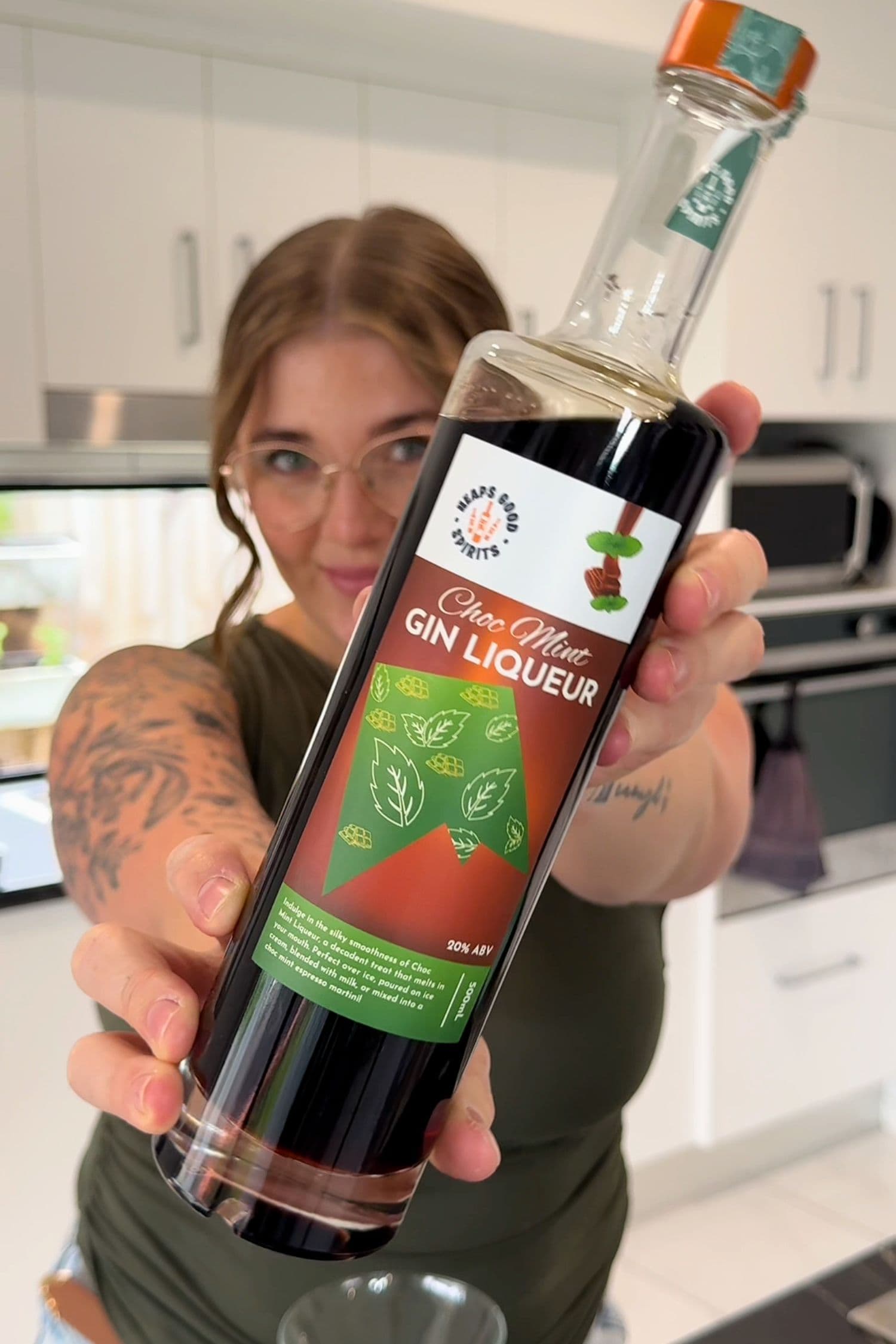 Customer holding Heaps Good Spirits Choc Mint Gin Liqueur bottle in kitchen setting