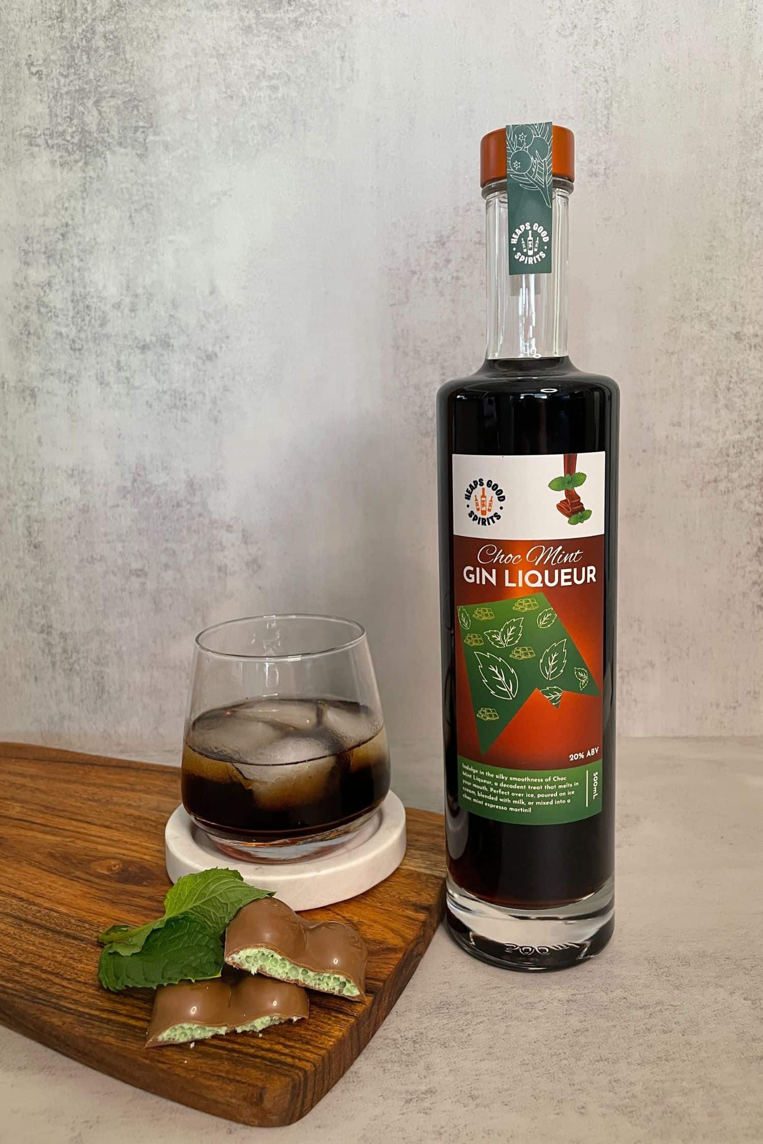 Choc Mint Gin Liqueur bottle styled with mint chocolate pieces and iced chocolate mint drink