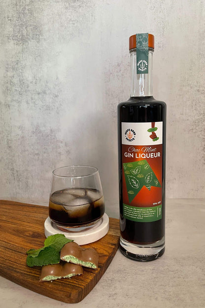 Choc Mint Gin Liqueur bottle styled with mint chocolate pieces and iced chocolate mint drink