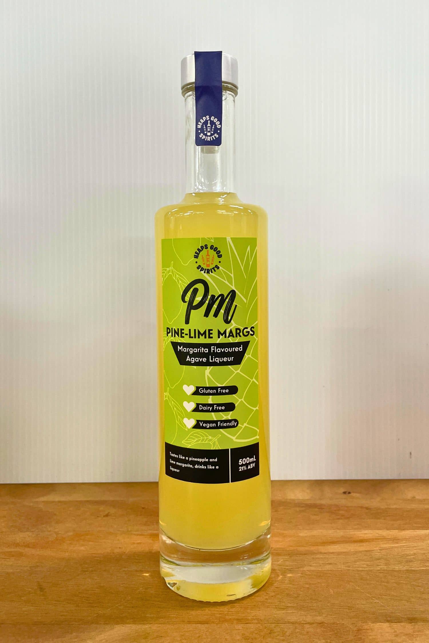 Heaps Good Pine-Lime Margs 500ml margarita flavoured agave liqueur bottle on wooden surface against white background