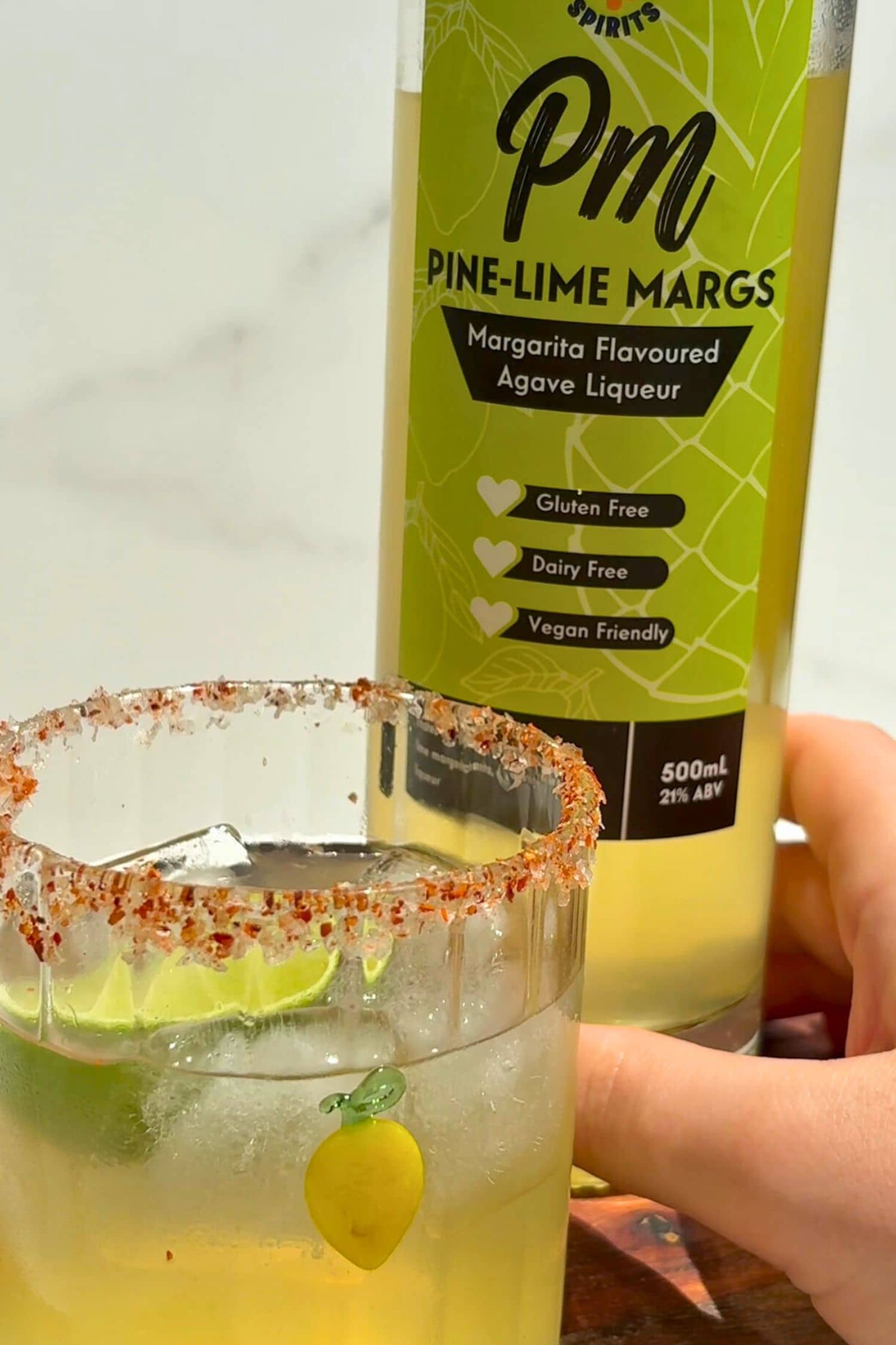 Heaps Good Pine-Lime Margs bottle beside margarita glass with chilli salt rim and lime garnish