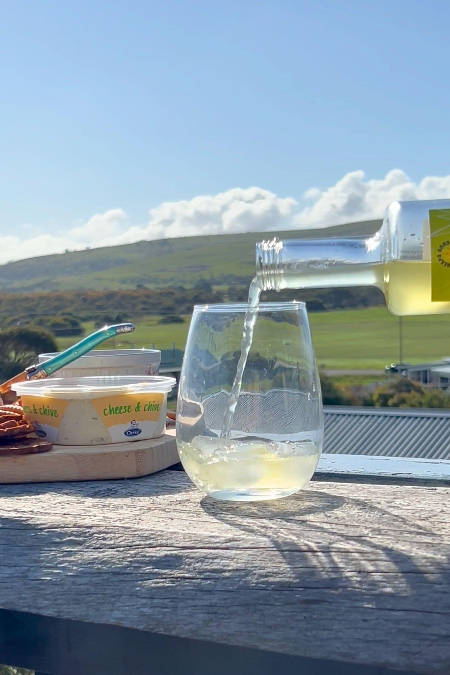Pineapple-Lime Margs being poured over ice, beside a grazing board