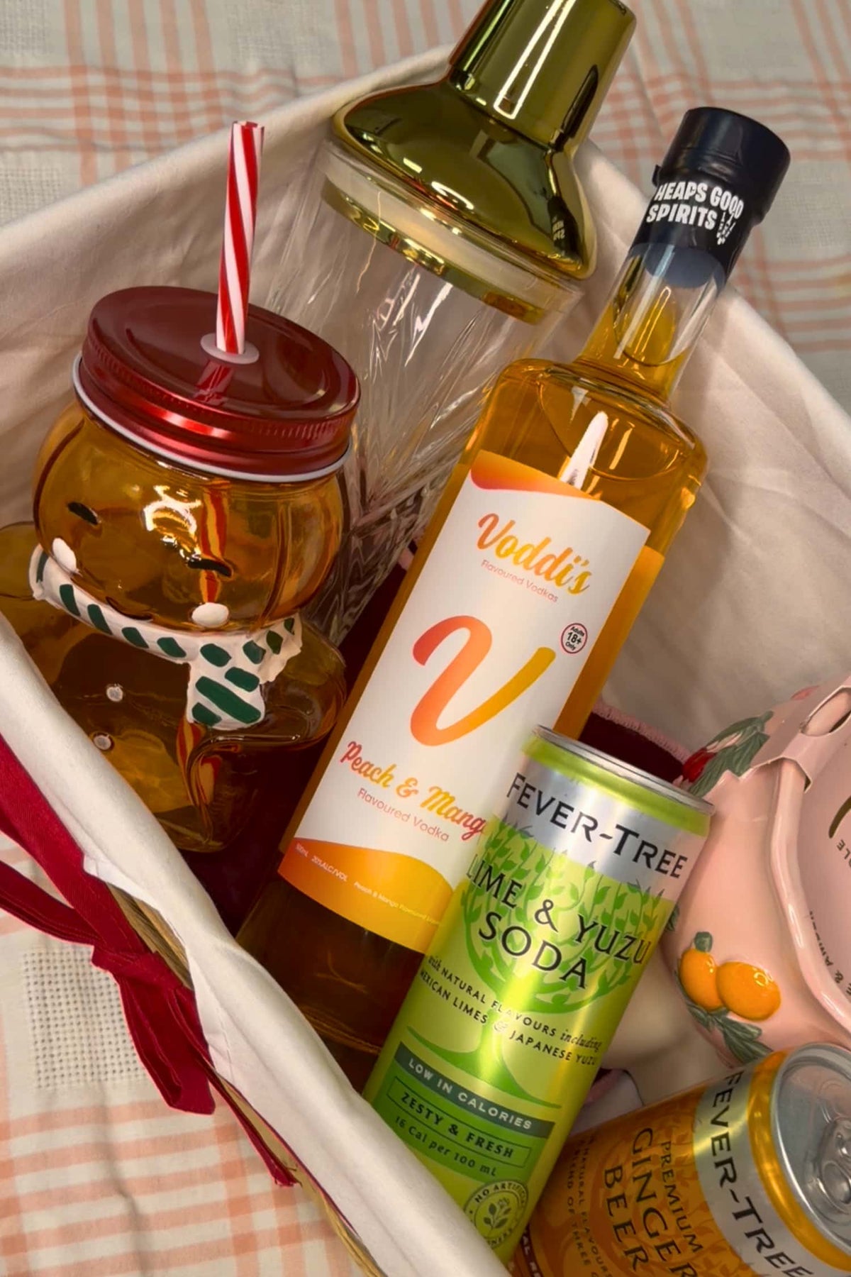 A curated gift basket containing multiple beverage-related items: a bottle of Vodd&