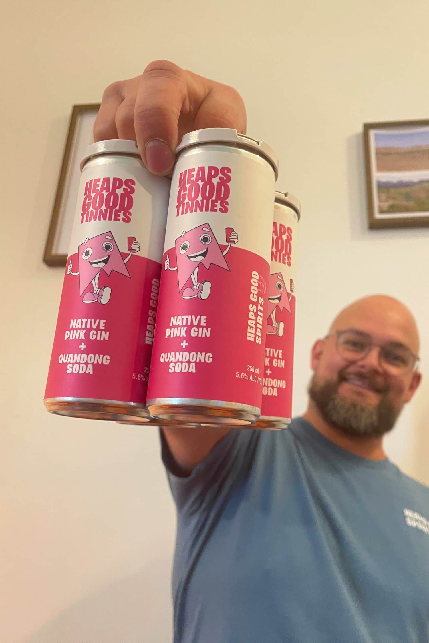 Heaps Good Spirits founder holding four pack of native pink gin and quandong soda ready to drink cans.