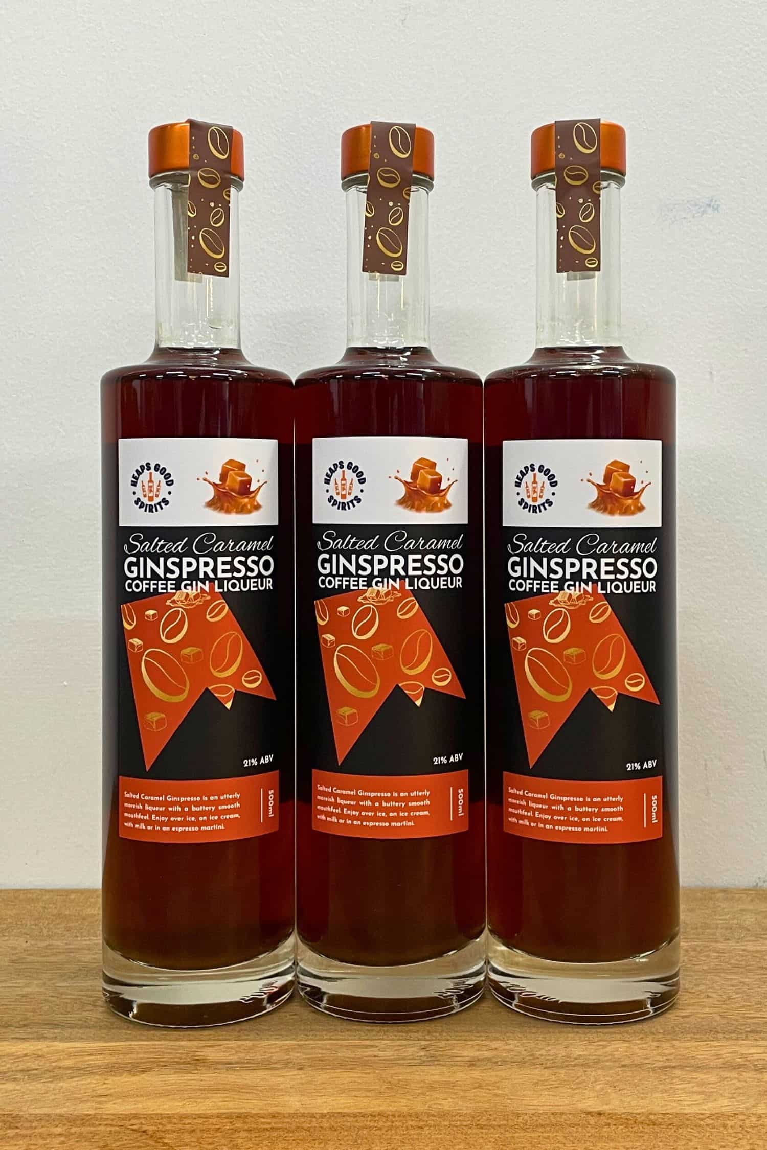 Three bottles of Salted Caramel Ginspresso coffee gin liqueur lined up on wooden surface