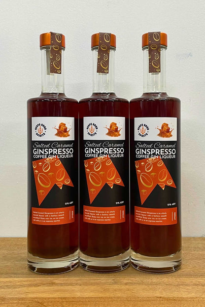 Three bottles of Salted Caramel Ginspresso coffee gin liqueur lined up on wooden surface