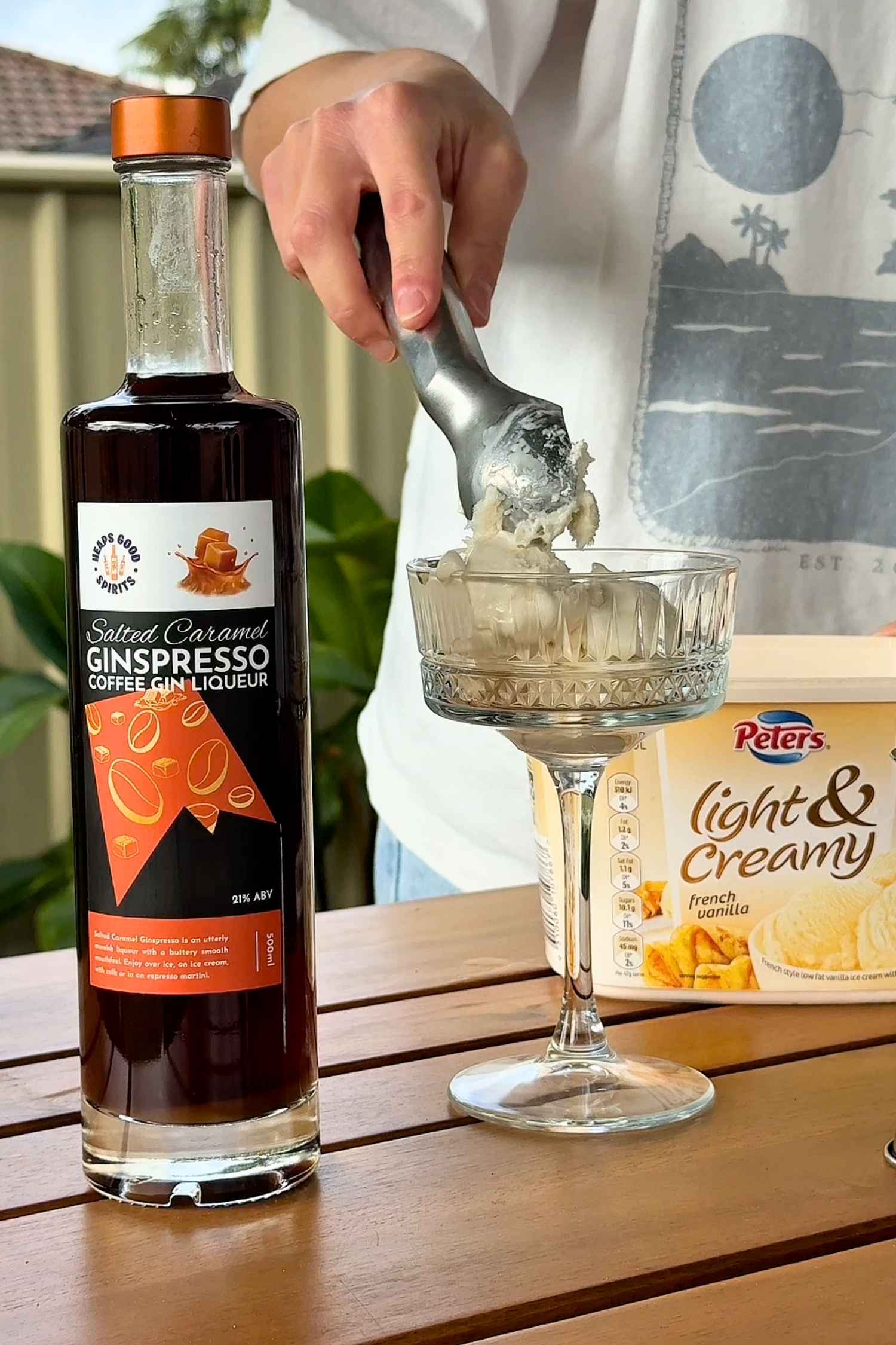 Bottle of Salted Caramel Ginspresso coffee gin liqueur beside a cocktail glass with ice cream being scooped into it.