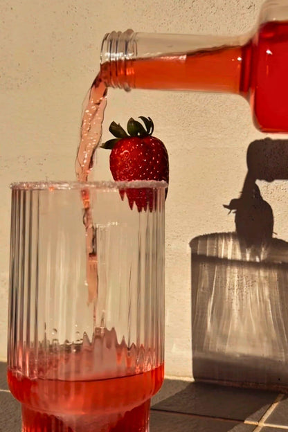 Heaps Good Strawberry Margs being poured into ribbed glass with salt rim and fresh strawberry garnish