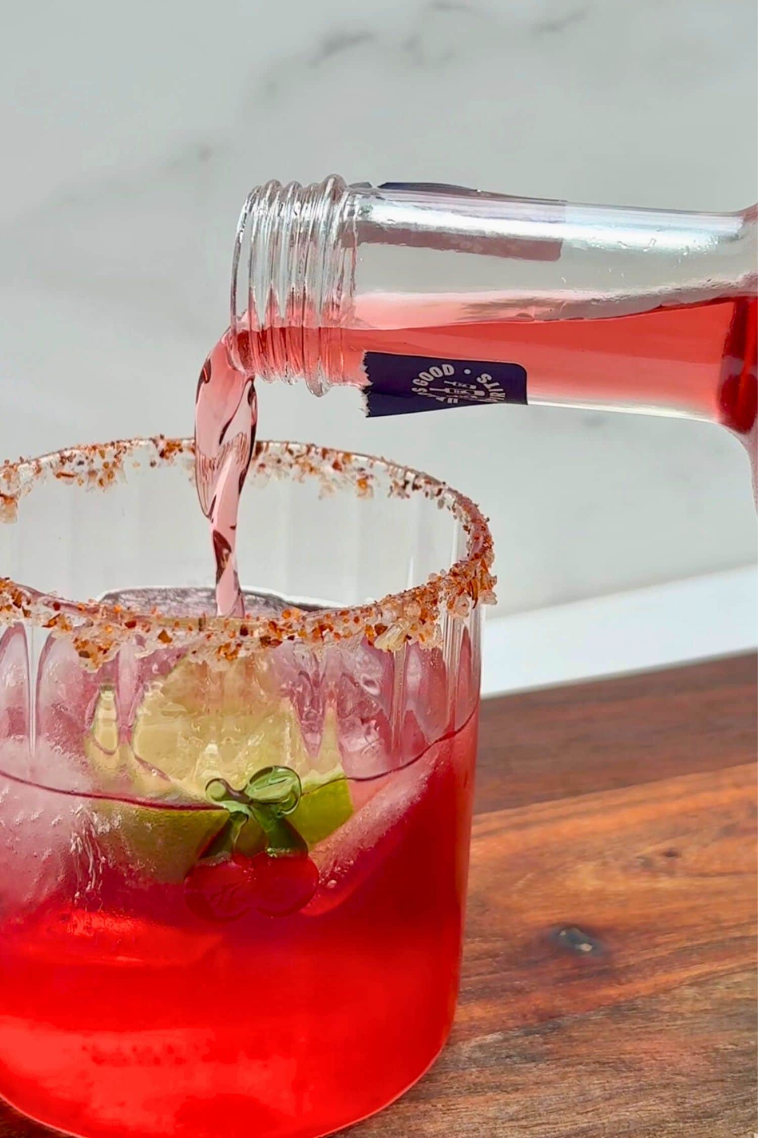 Strawberry margarita with chilli salt rim and lime wedge being topped with Heaps Good Strawberry Margs