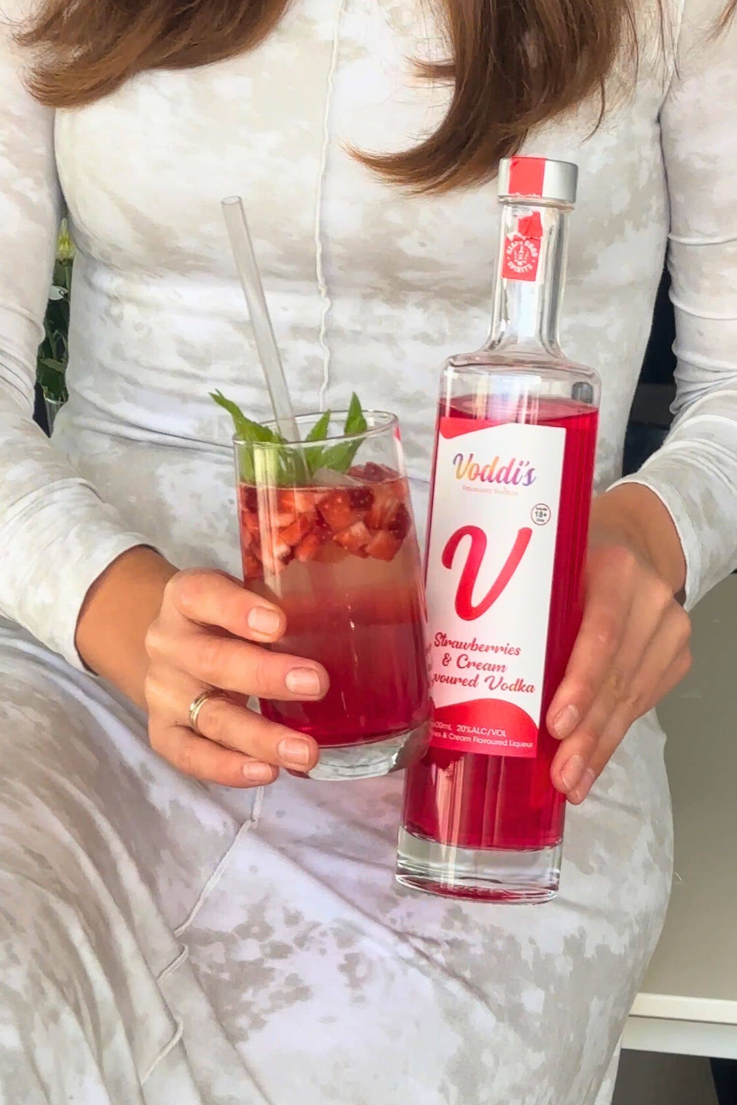 Strawberries &amp; Cream Vodka strawberry soda cocktail with fresh mint and diced strawberries beside Voddi’s bottle.